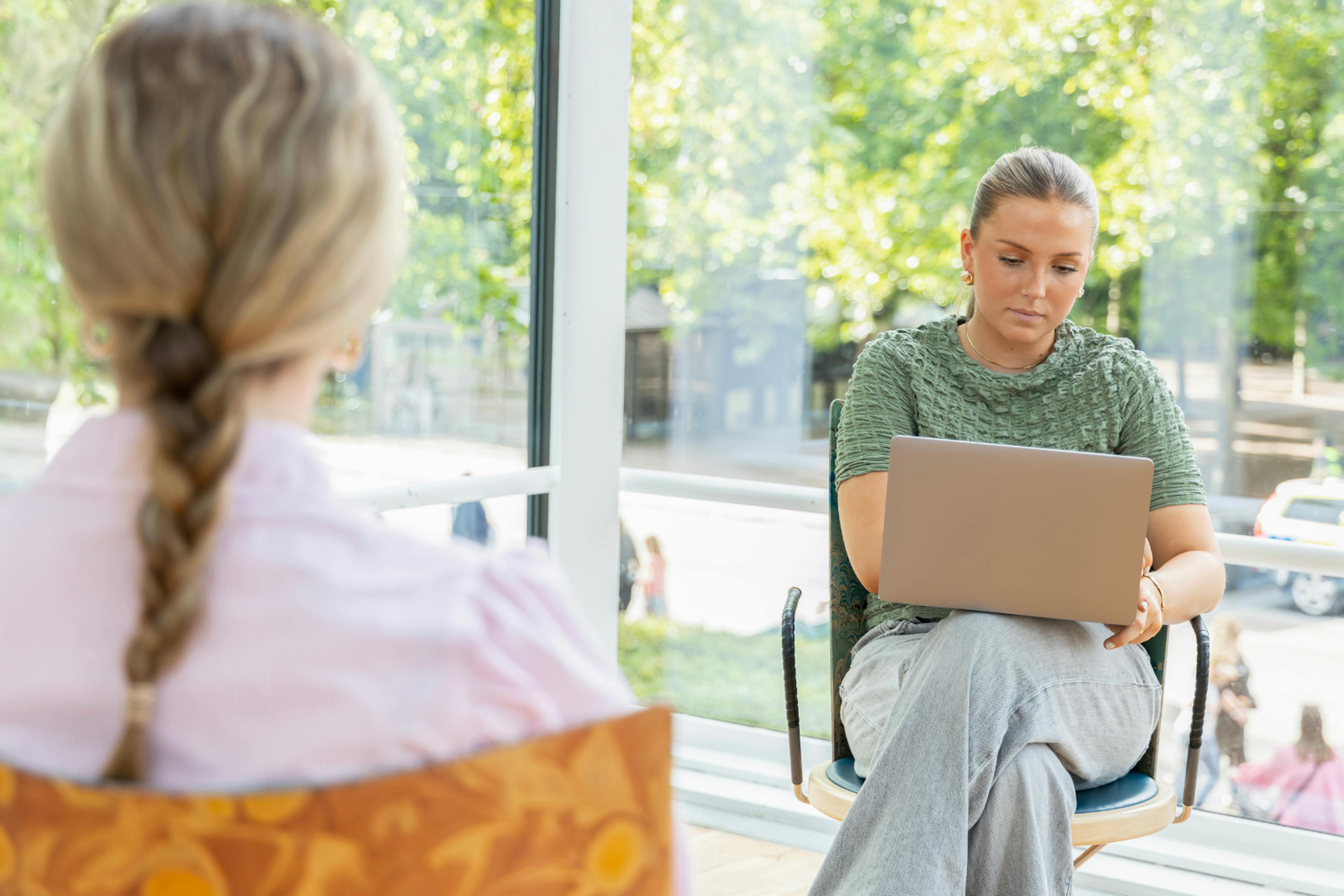 two girls one with a laptop on their knee