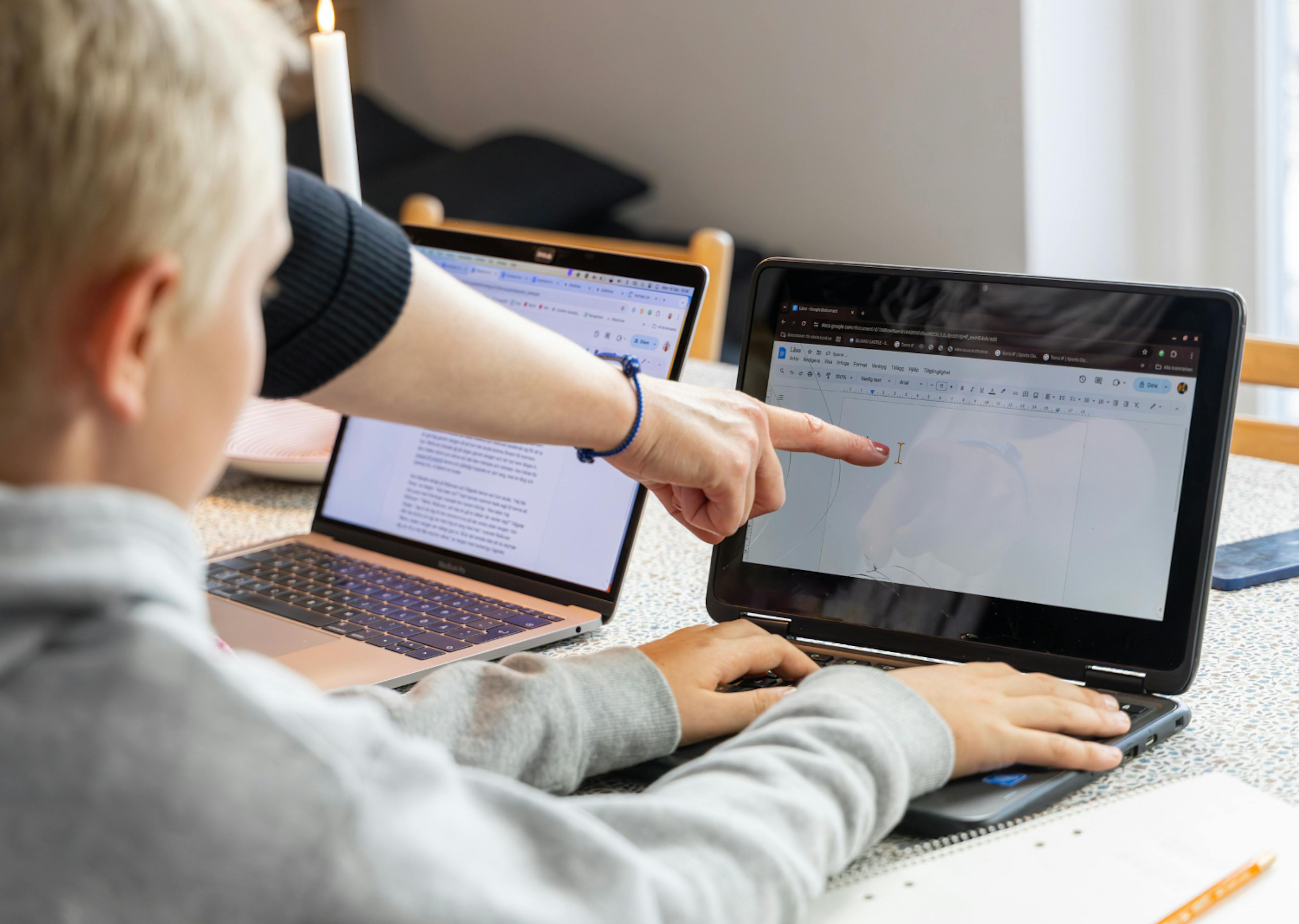 a teacher pointing at something on a laptop