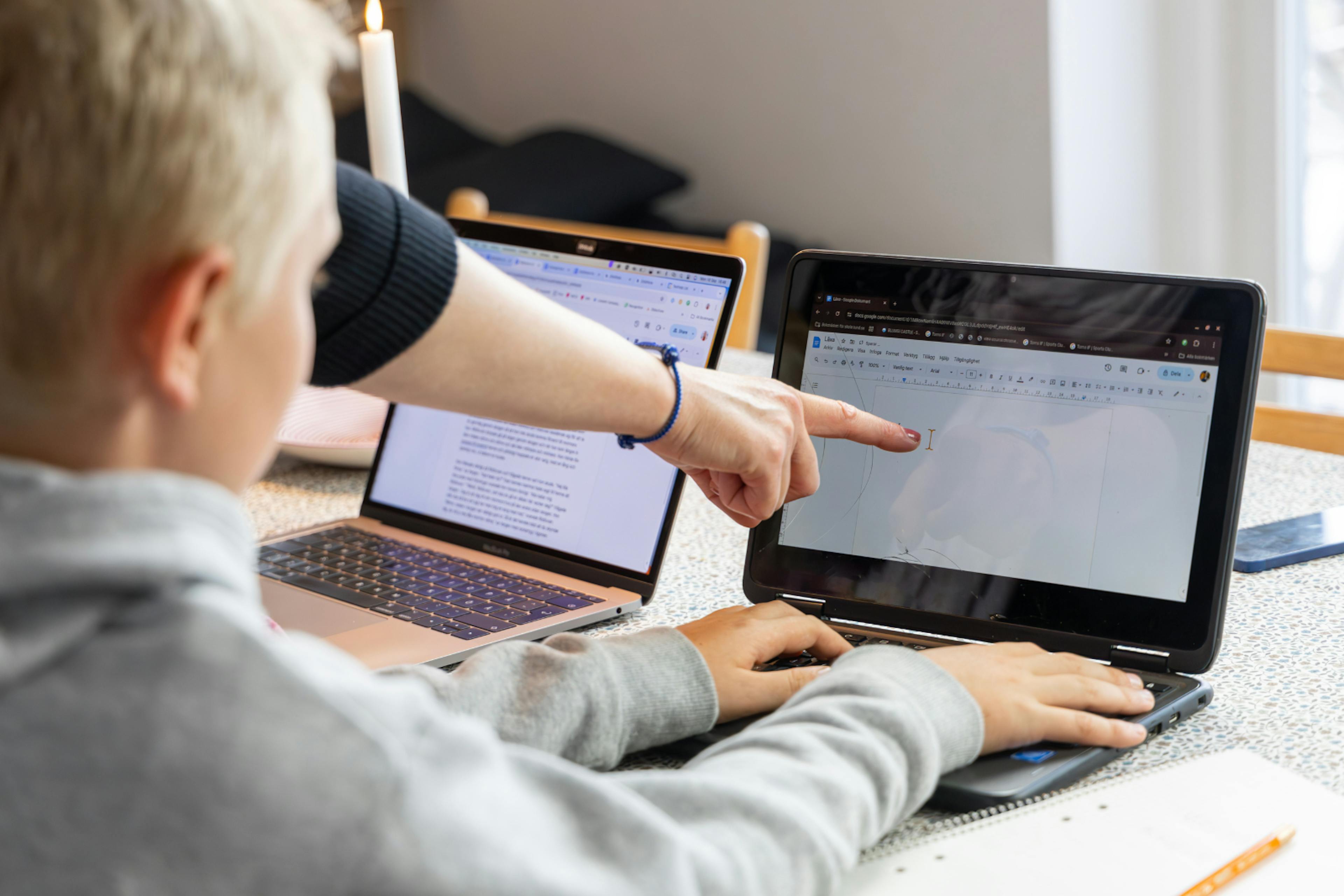 a teacher pointing at something on a laptop