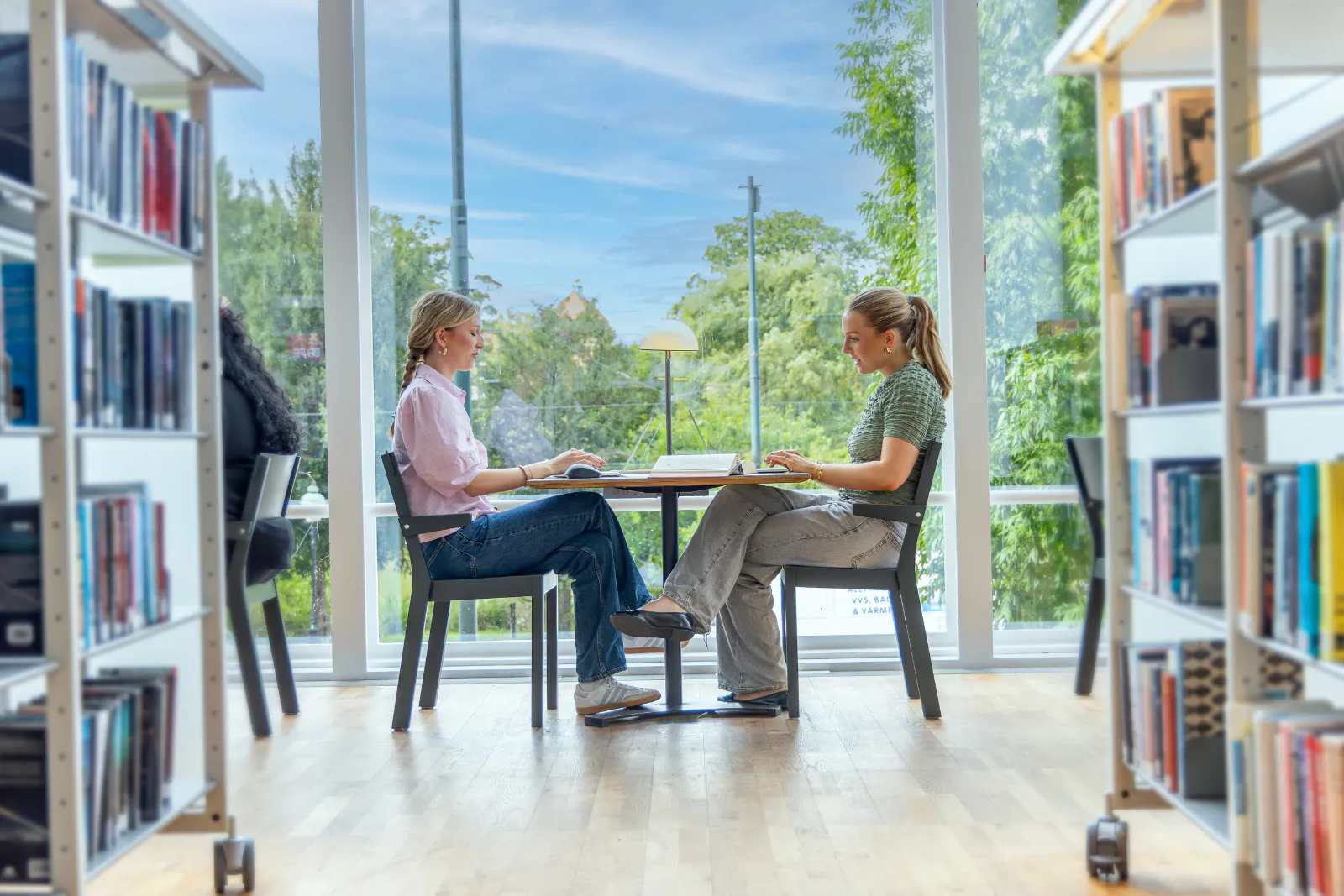 two girls sitting facing each other in a library
