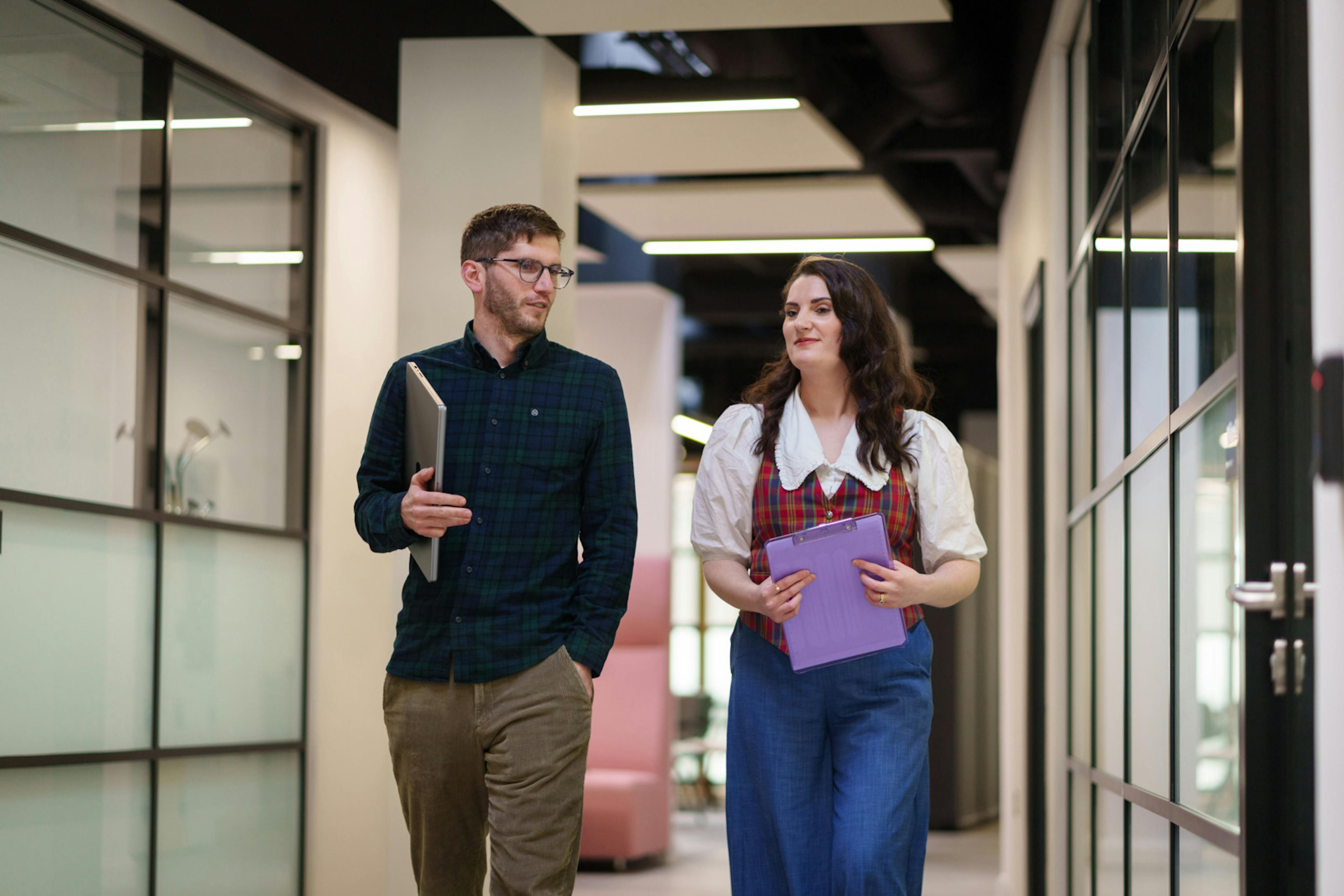 2 employees walking in an office hallway