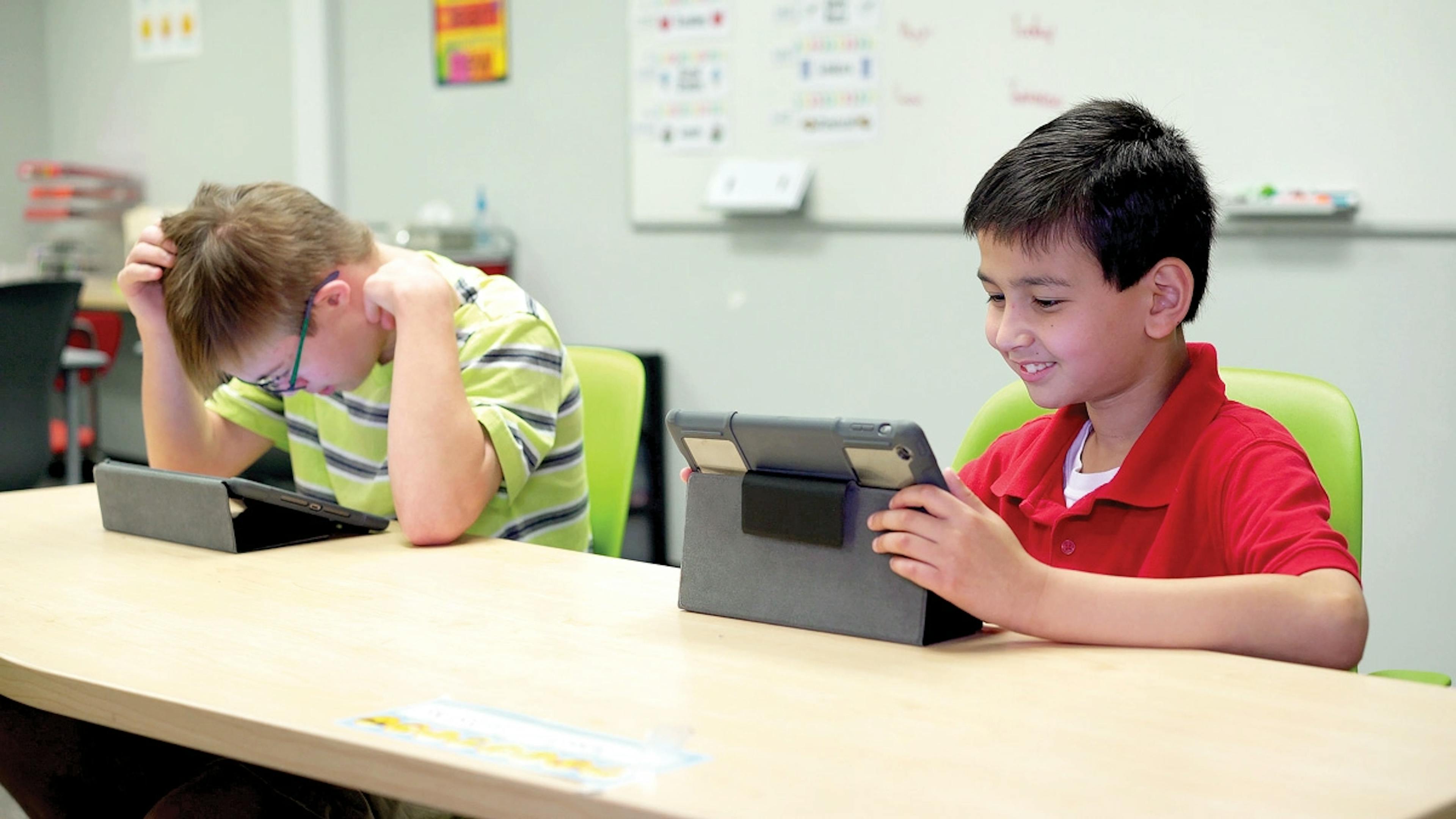 2 students at a desk working on devices