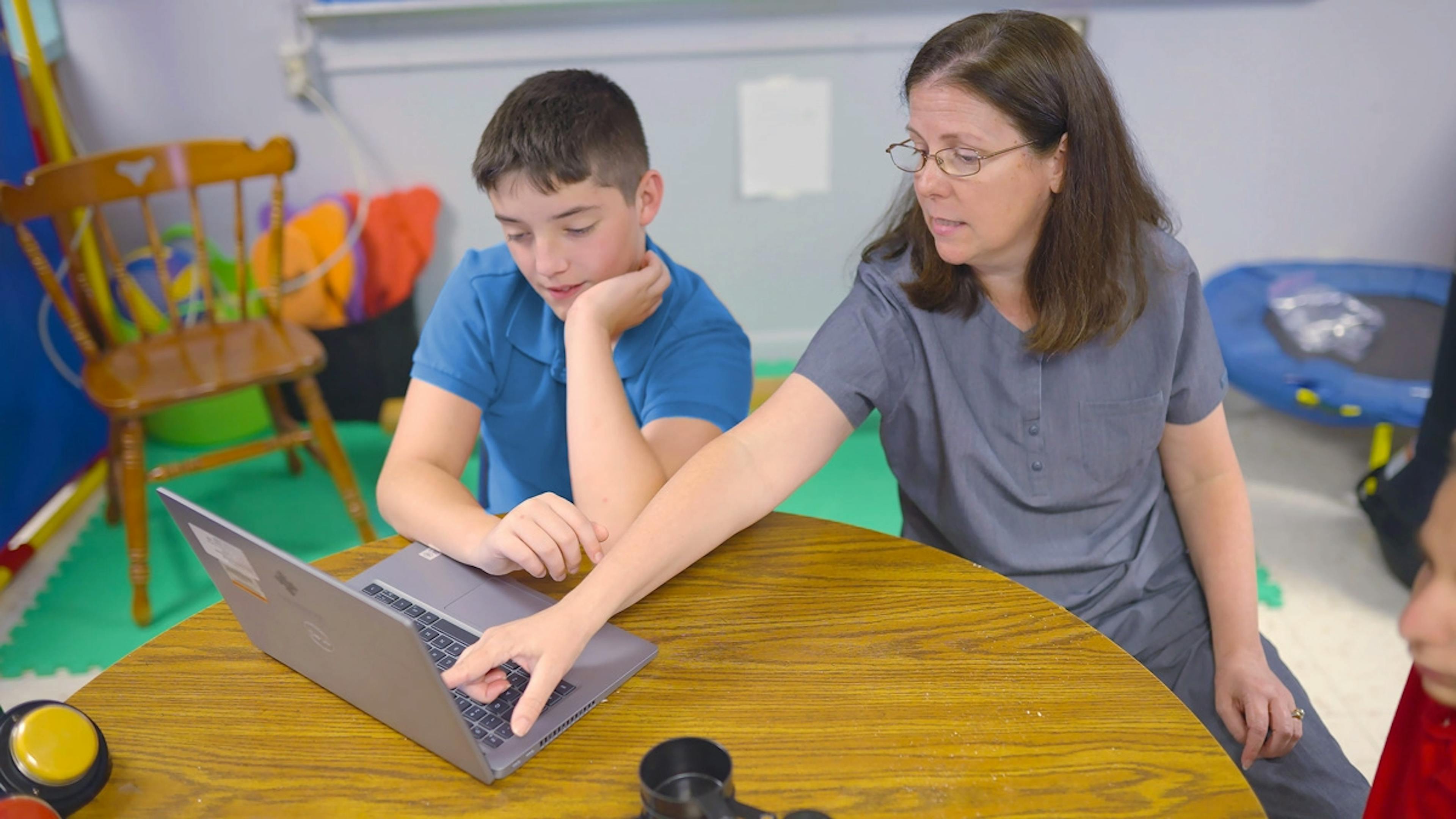 A student and teacher working at a desk on a laptop