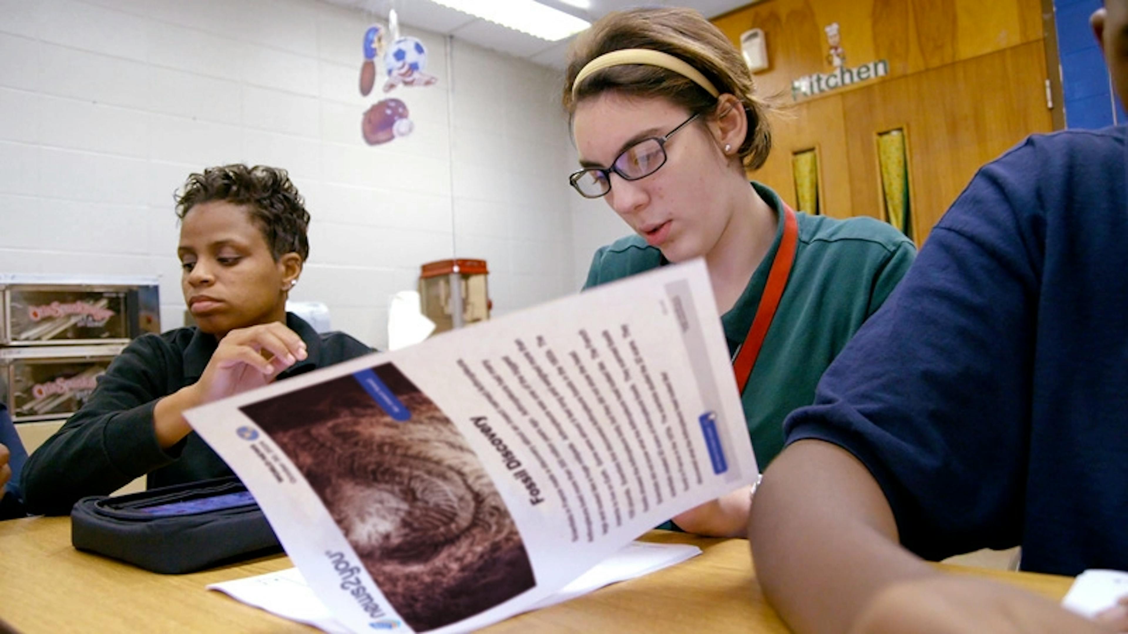 A student with glasses working at a desk