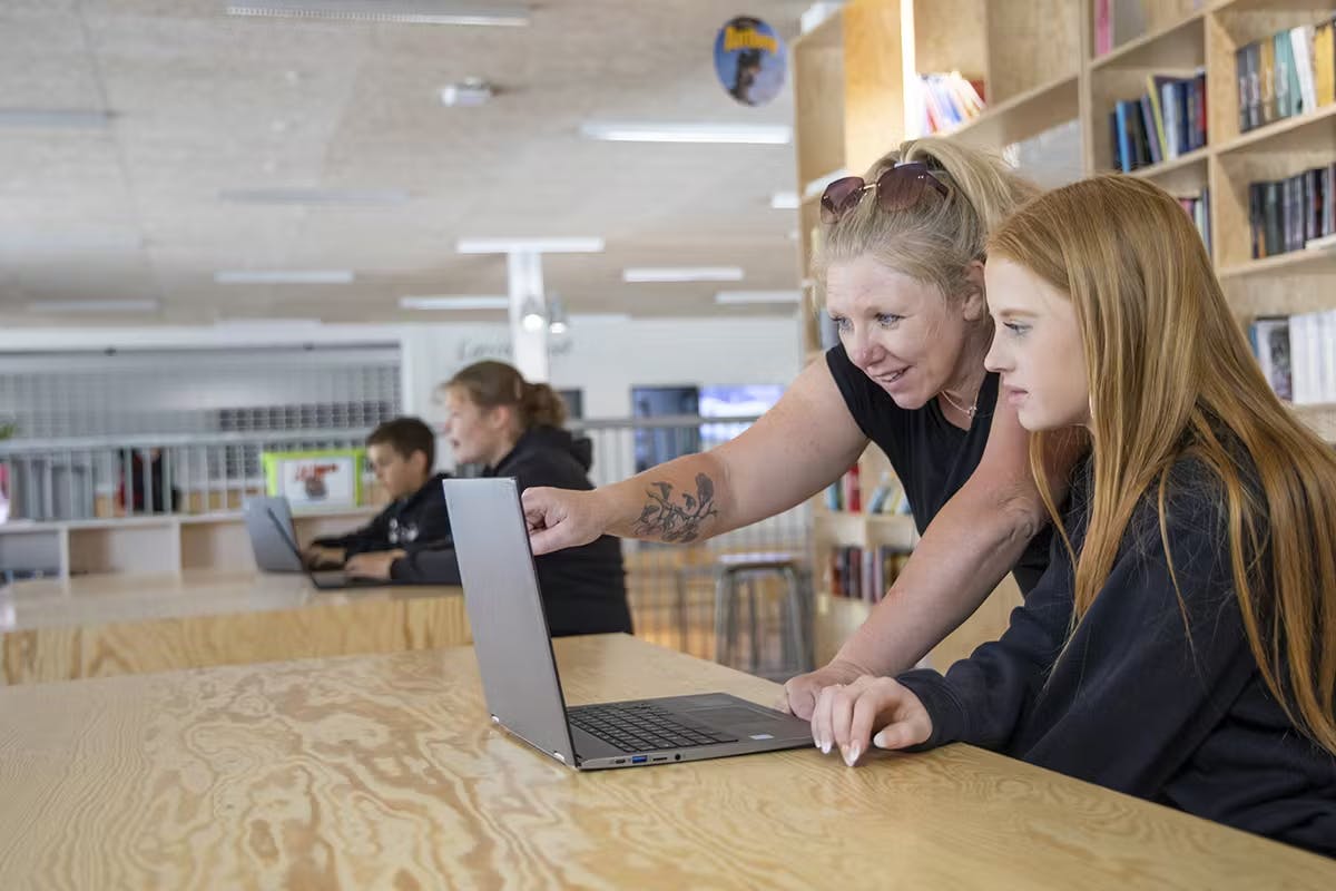 En lärare hjälper en elev att använda en bärbar dator