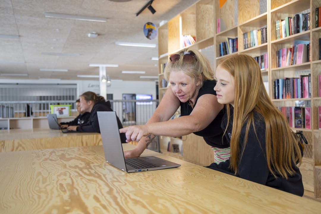 en lærer taler med en elev ved hjælp af en bærbar computer