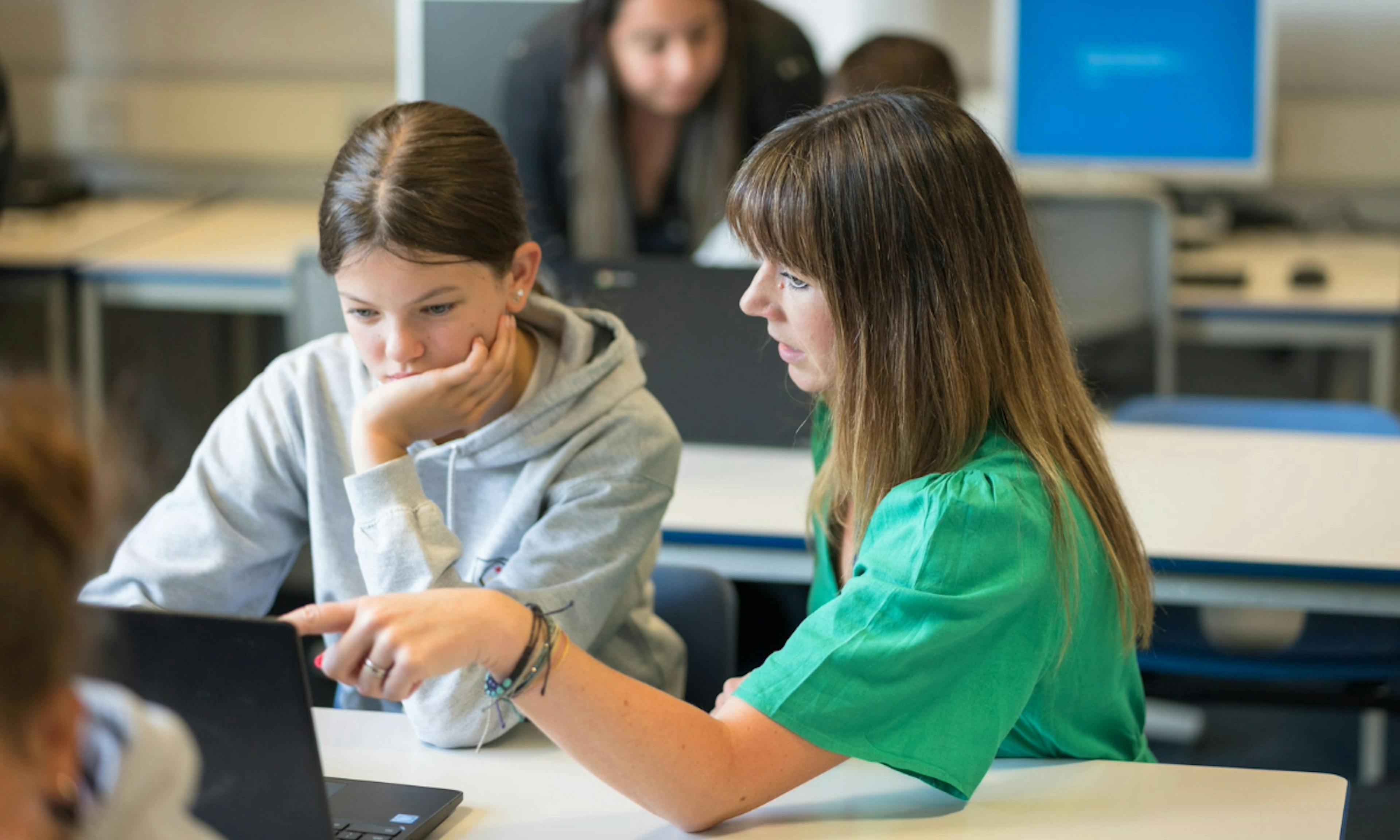 A teacher and a student using a laptop