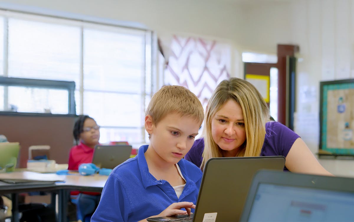 A teacher and a student looking at a laptop