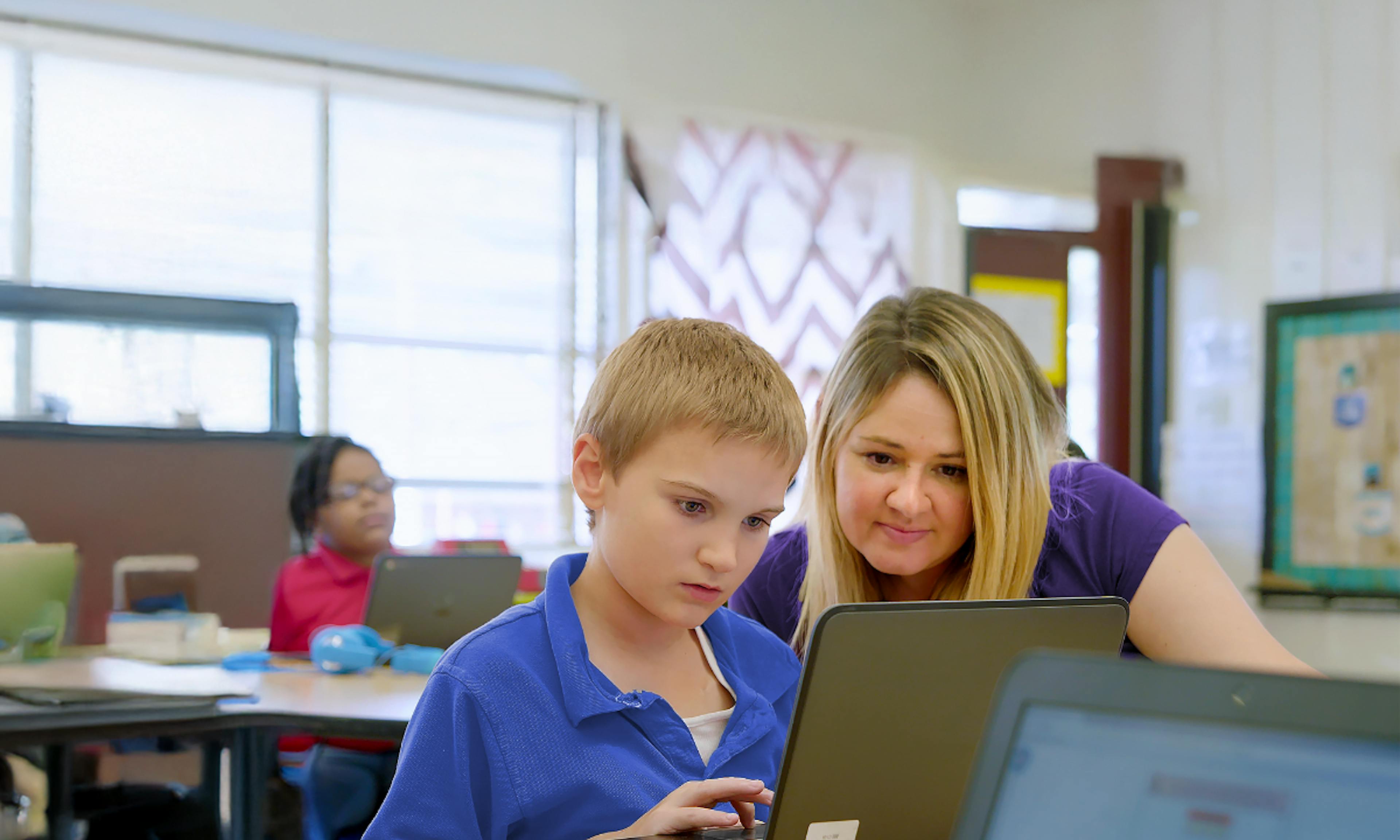 A teacher and a student looking at a laptop