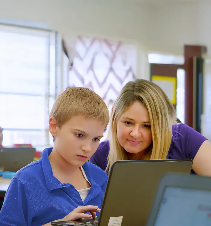 A teacher and a student looking at a laptop