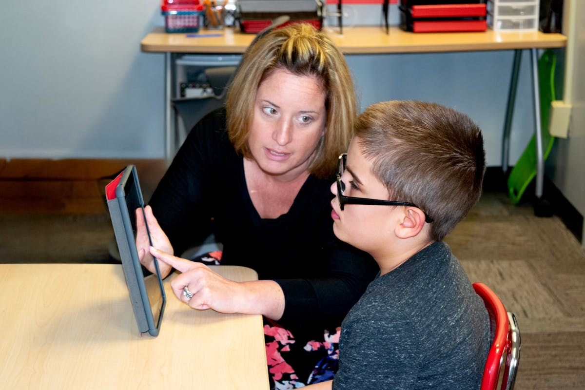 Student and a teacher looking at a tablet