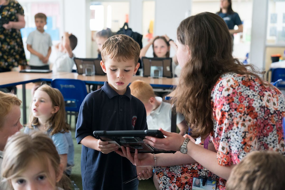 A student in a busy classroom getting help from a teacher