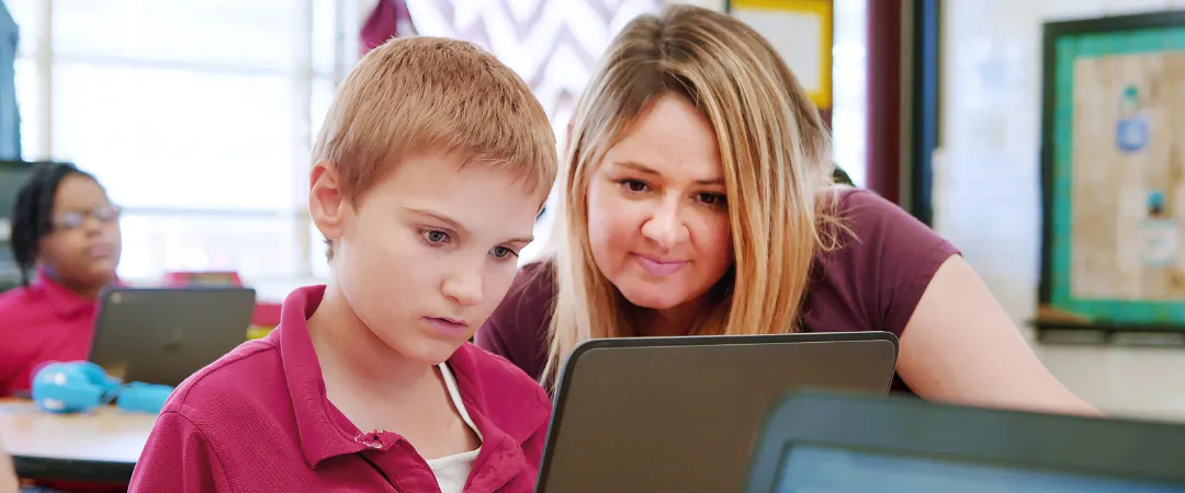 A student and a teacher looking at a laptop