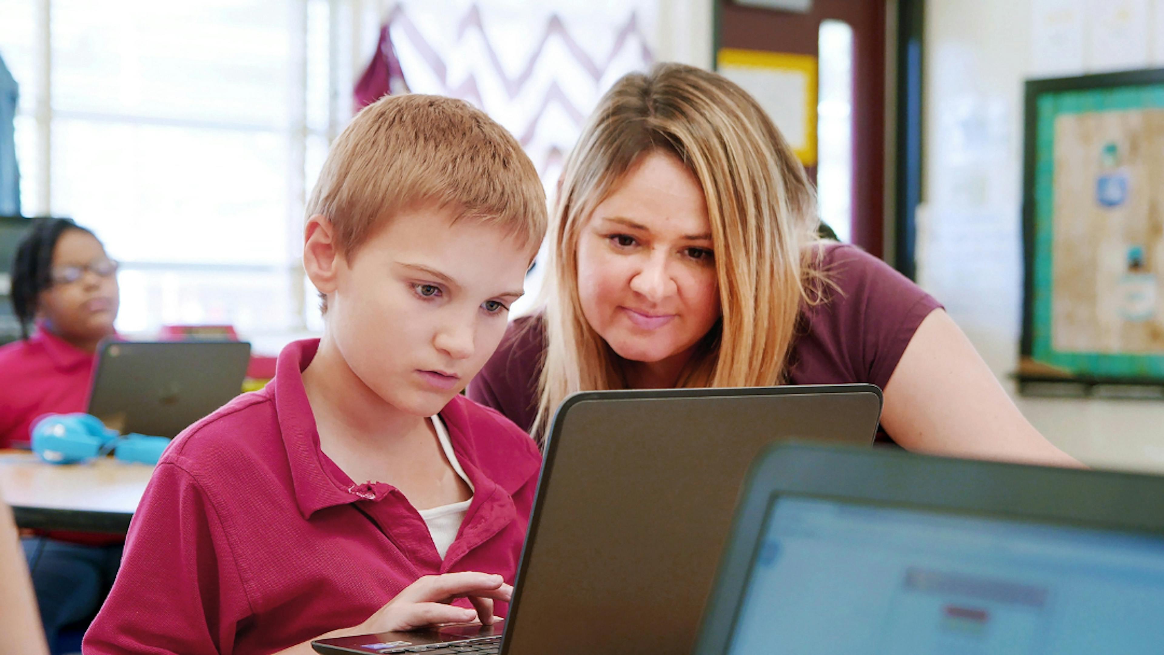 A student and a teacher looking at a laptop