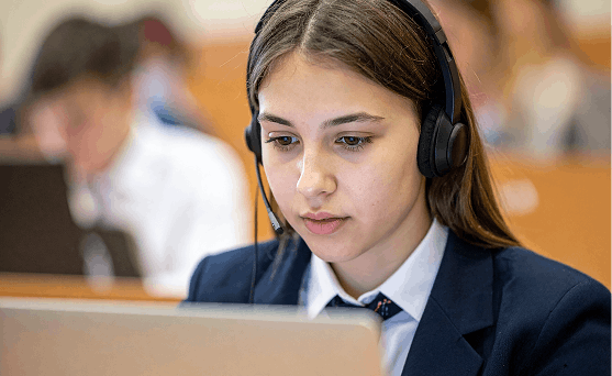 Student working on a laptop wearing a headset.