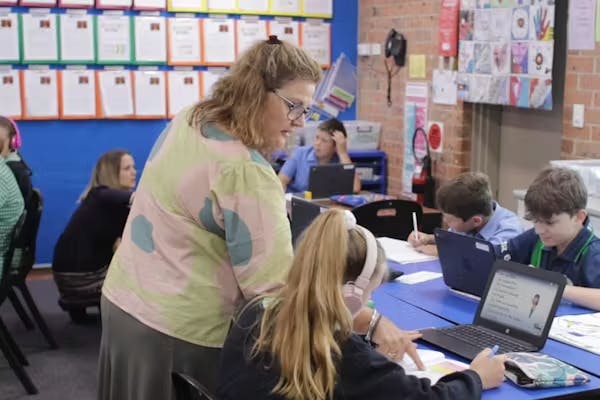 A teacher helping a student with work in a classroom