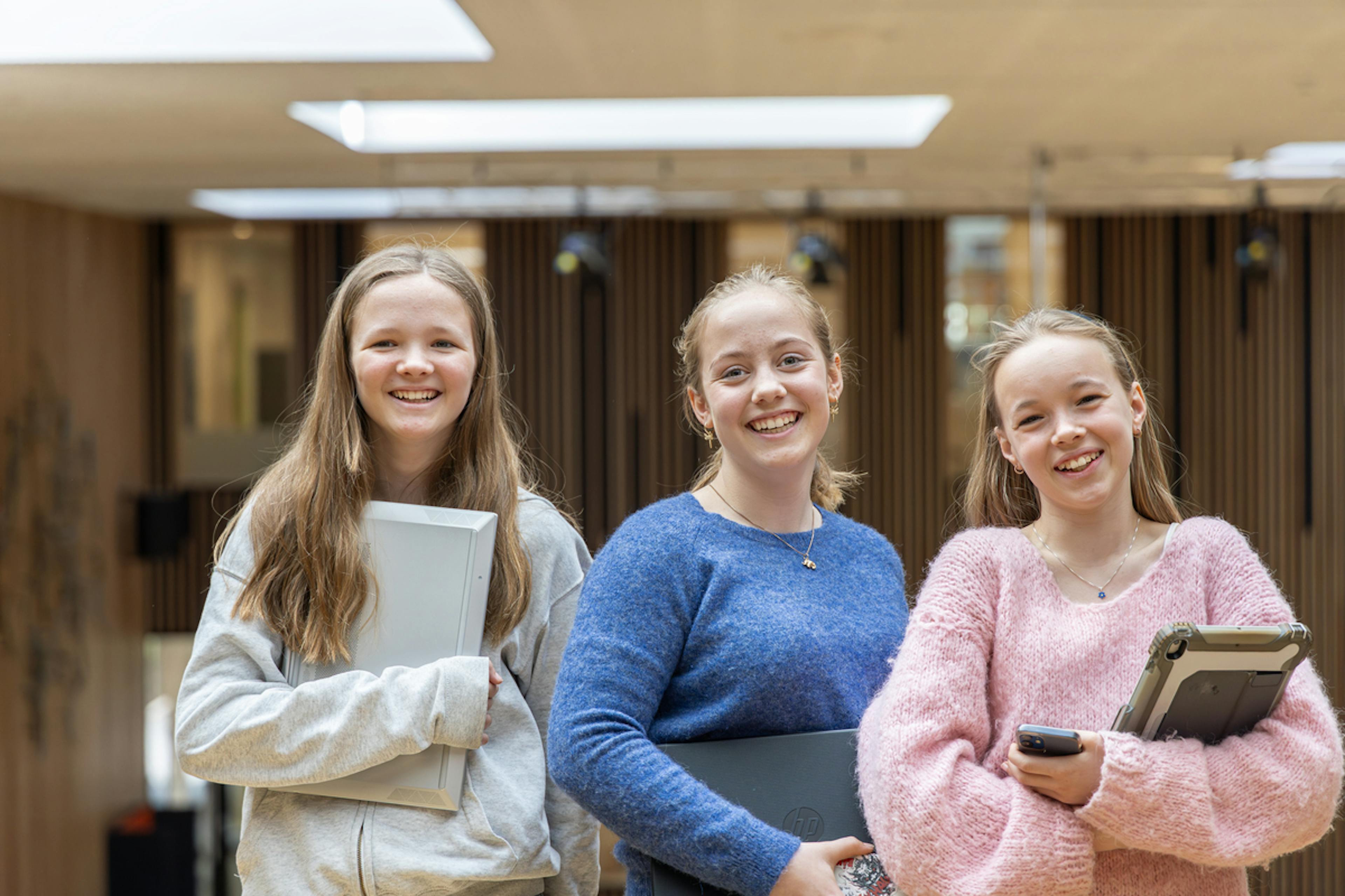 Tre elever på skolen smiler
