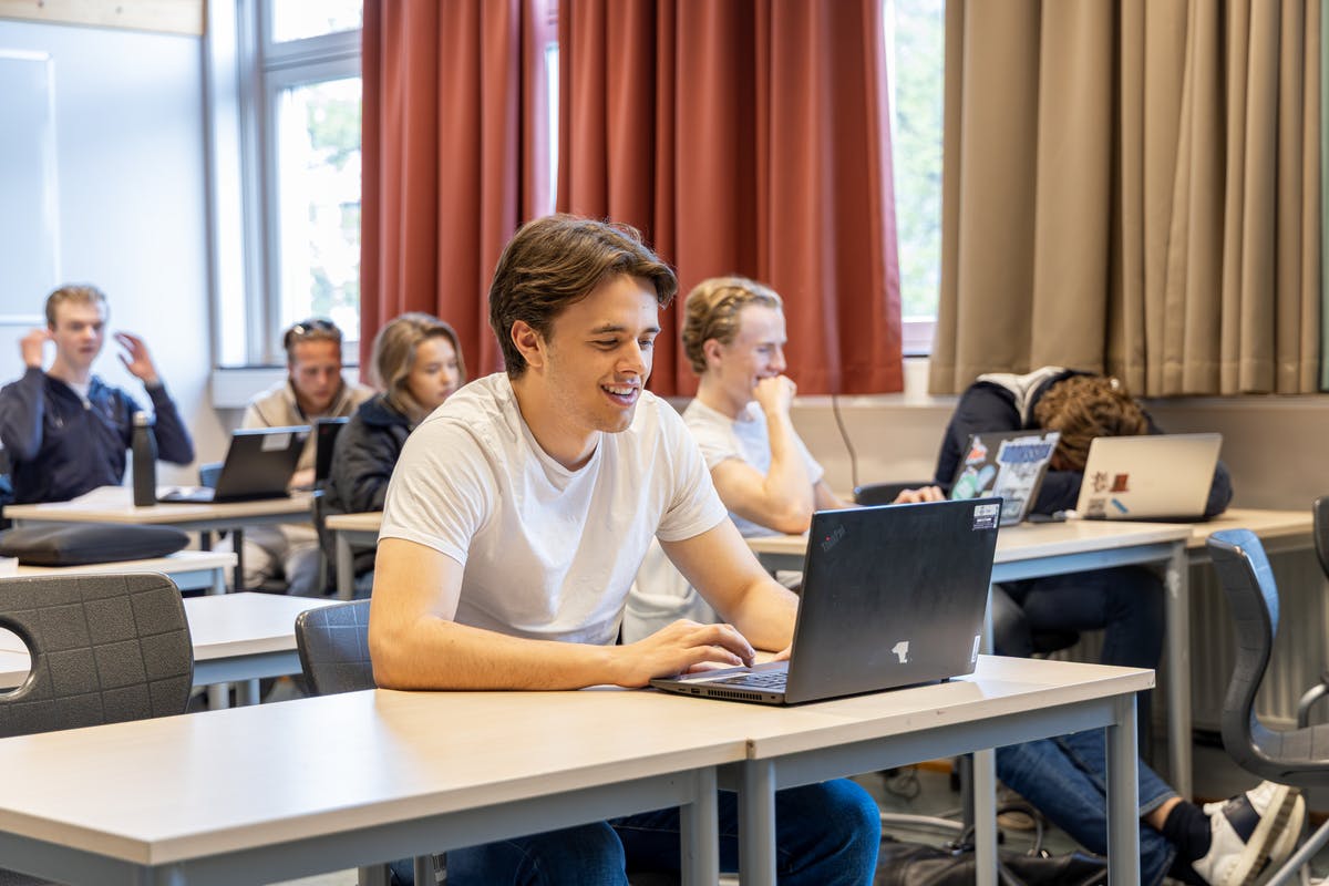 A student sitting in a classroom with a laptop on the desk
