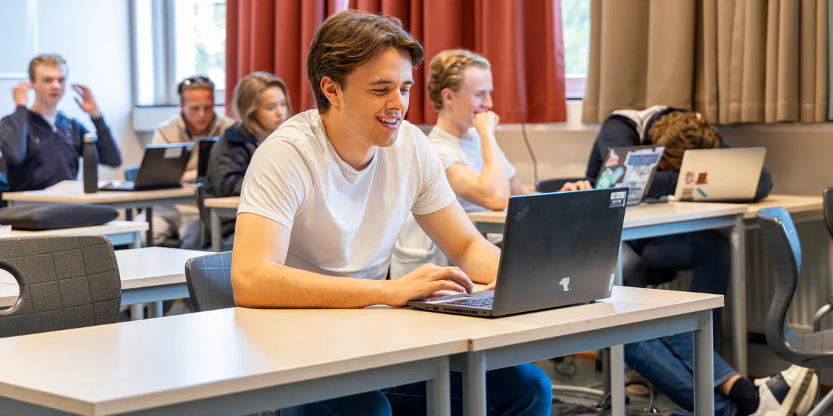 En student sitter i et klasserom med en bærbar PC