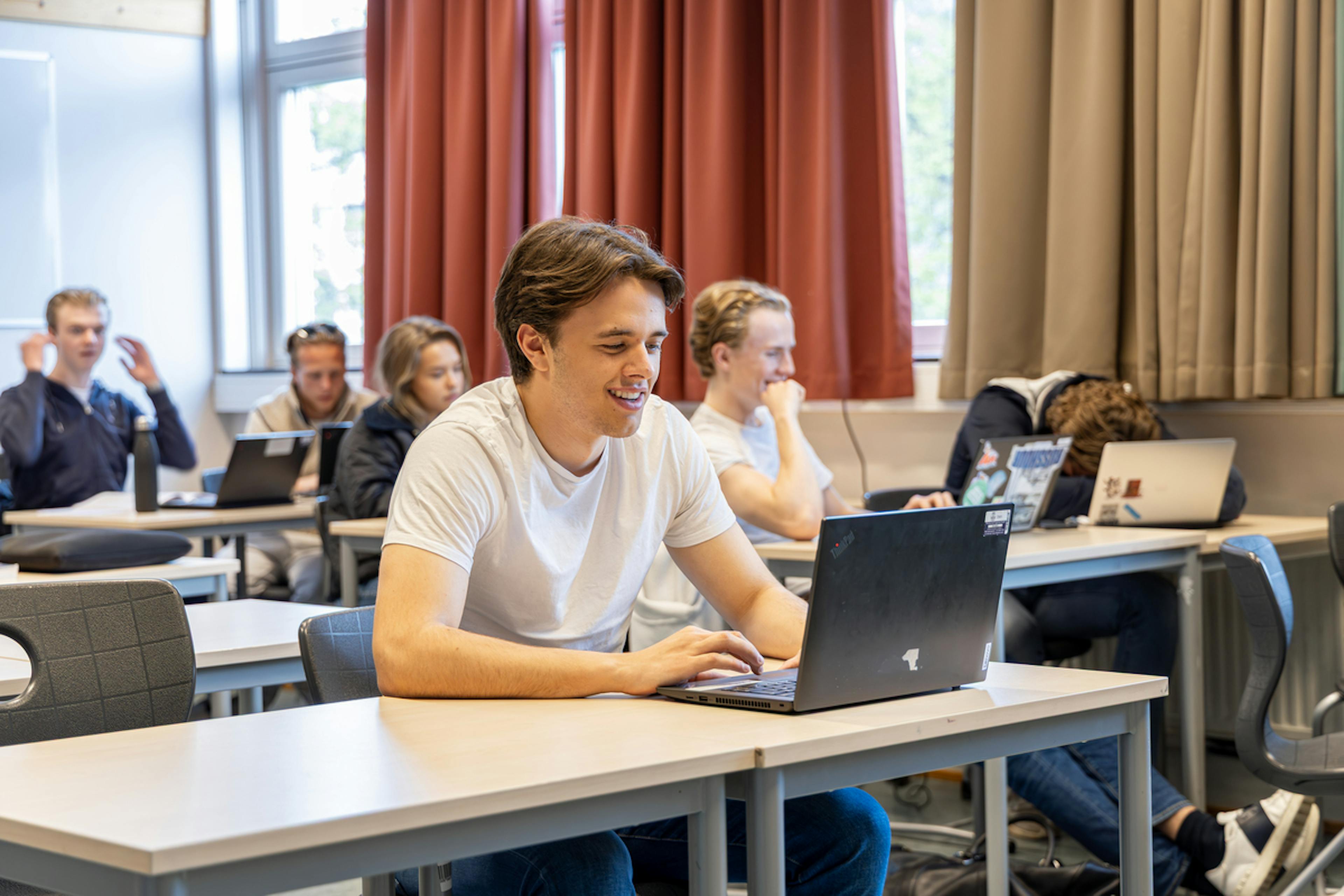 A student sitting in a classroom with a laptop on the desk