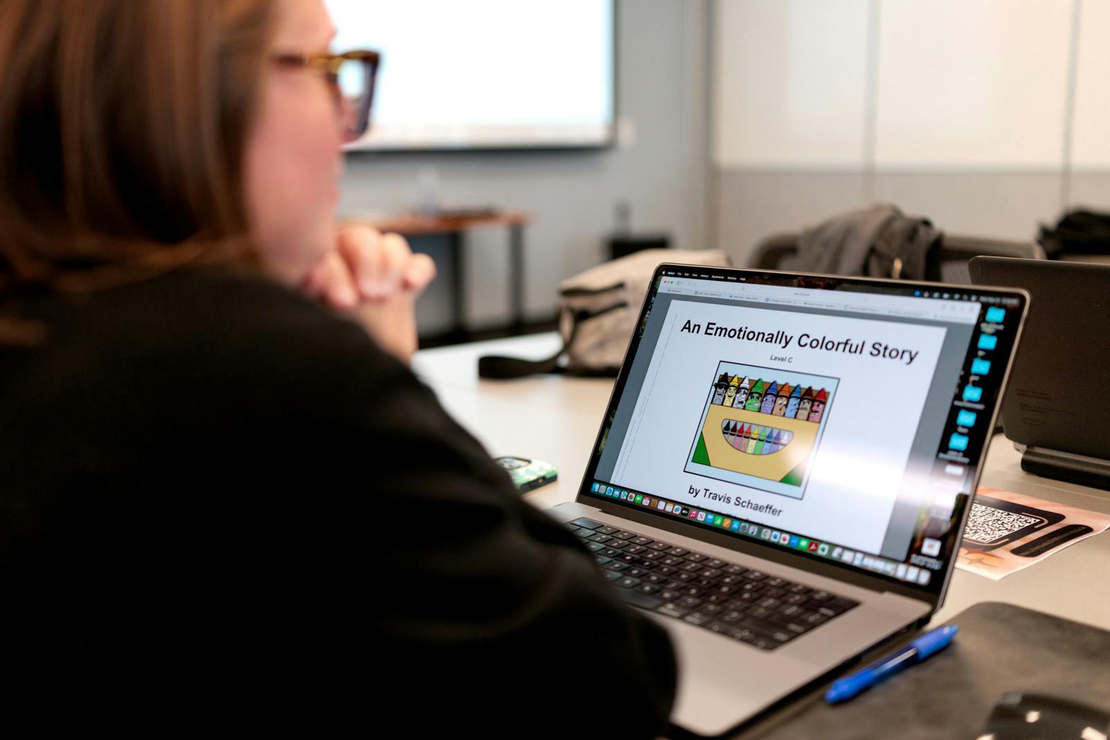 Person viewing a laptop screen displaying a slide titled “An Emotionally Colorful Story” with an image of crayons, during a training session.