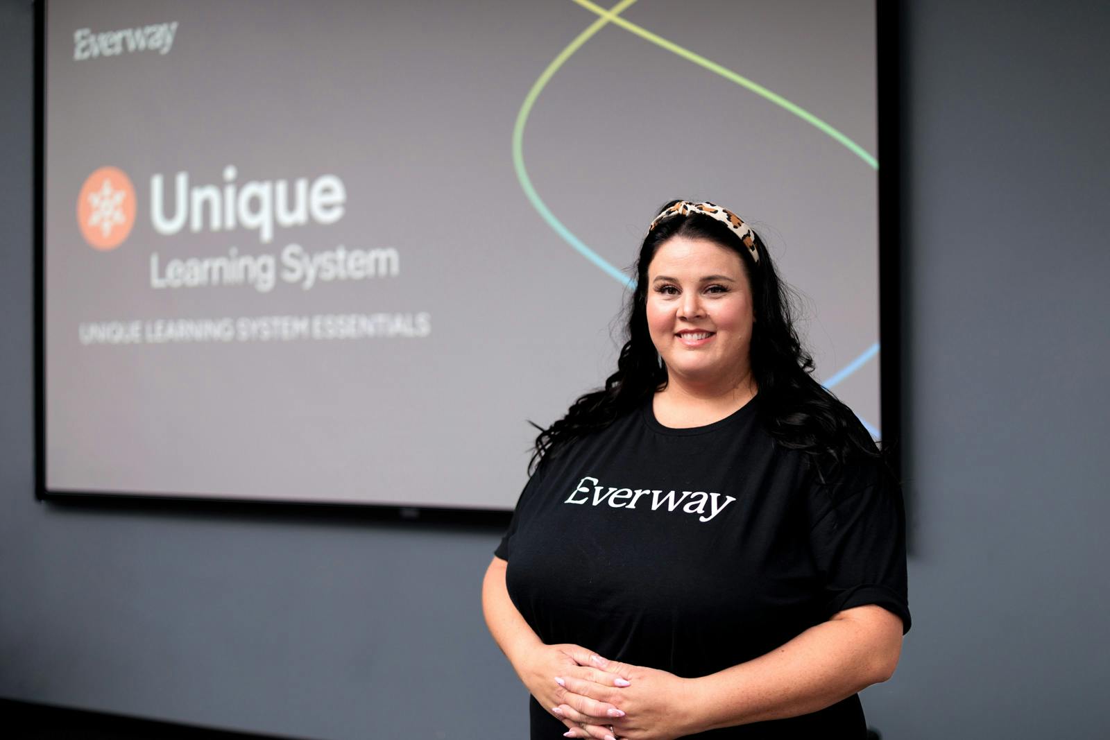 Woman standing in front of an Everway presentation slide titled “Unique Learning System,” smiling at the camera during a workshop.