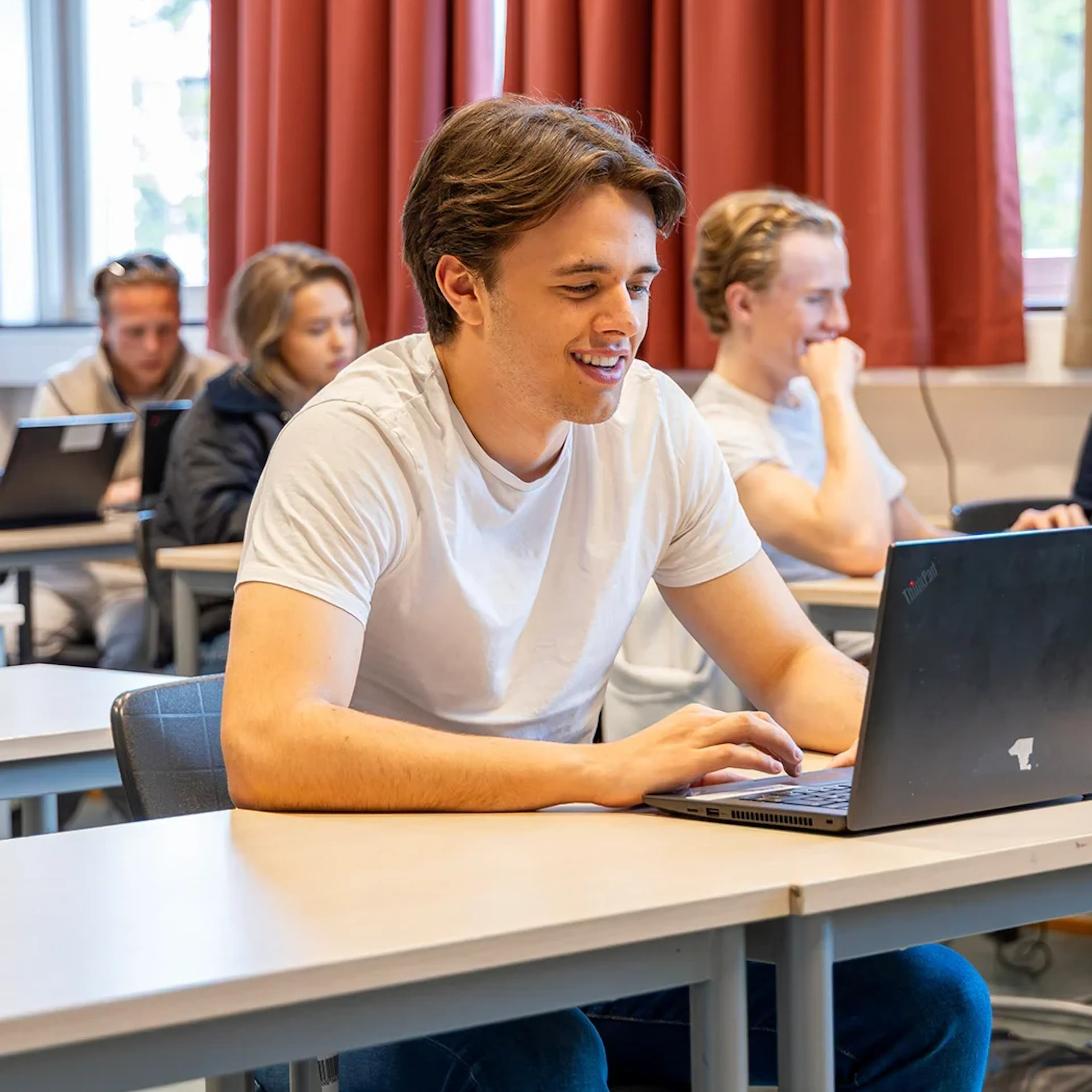 A student with their laptop sitting at a desk in a classroom