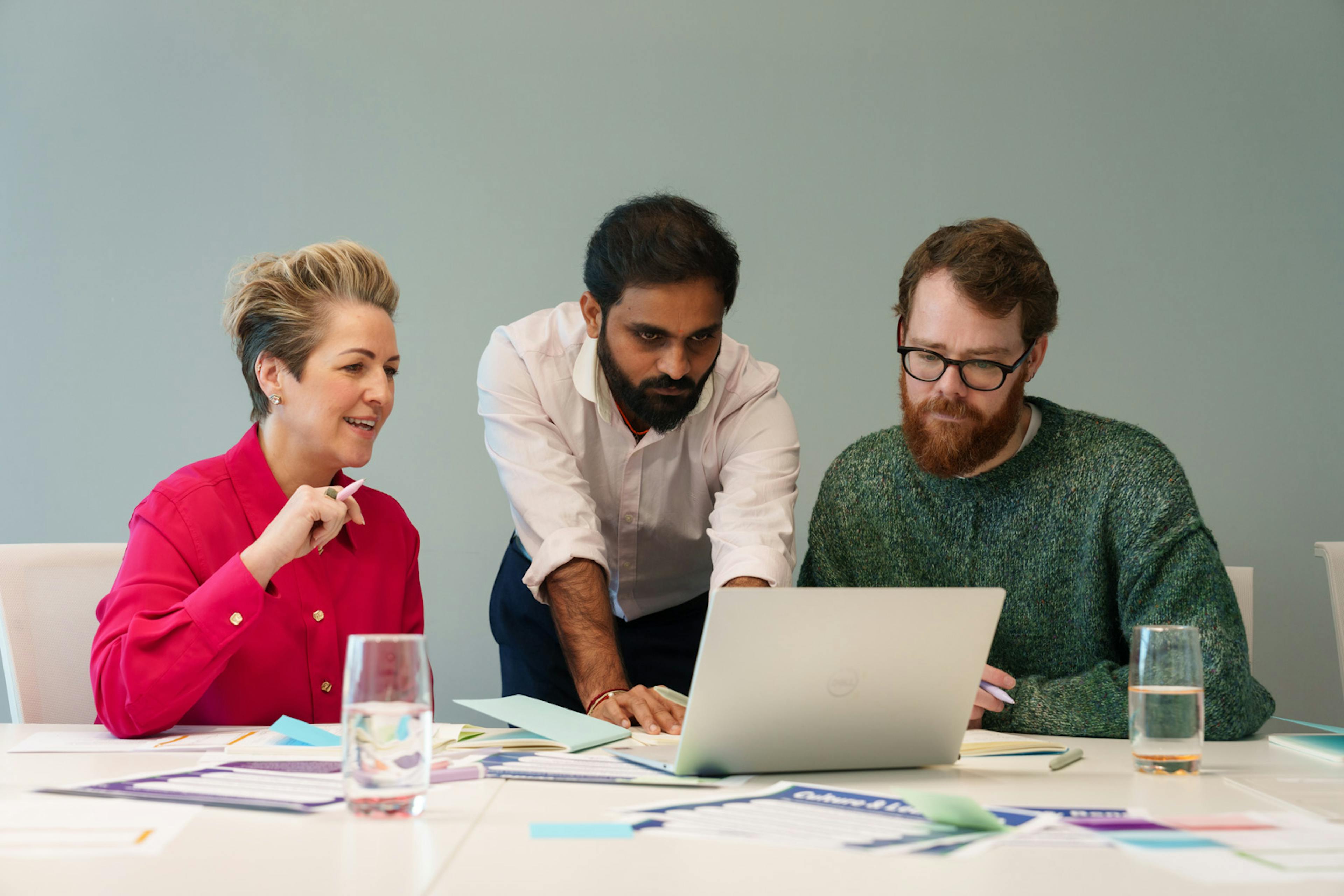 3 employees gathered around a laptop