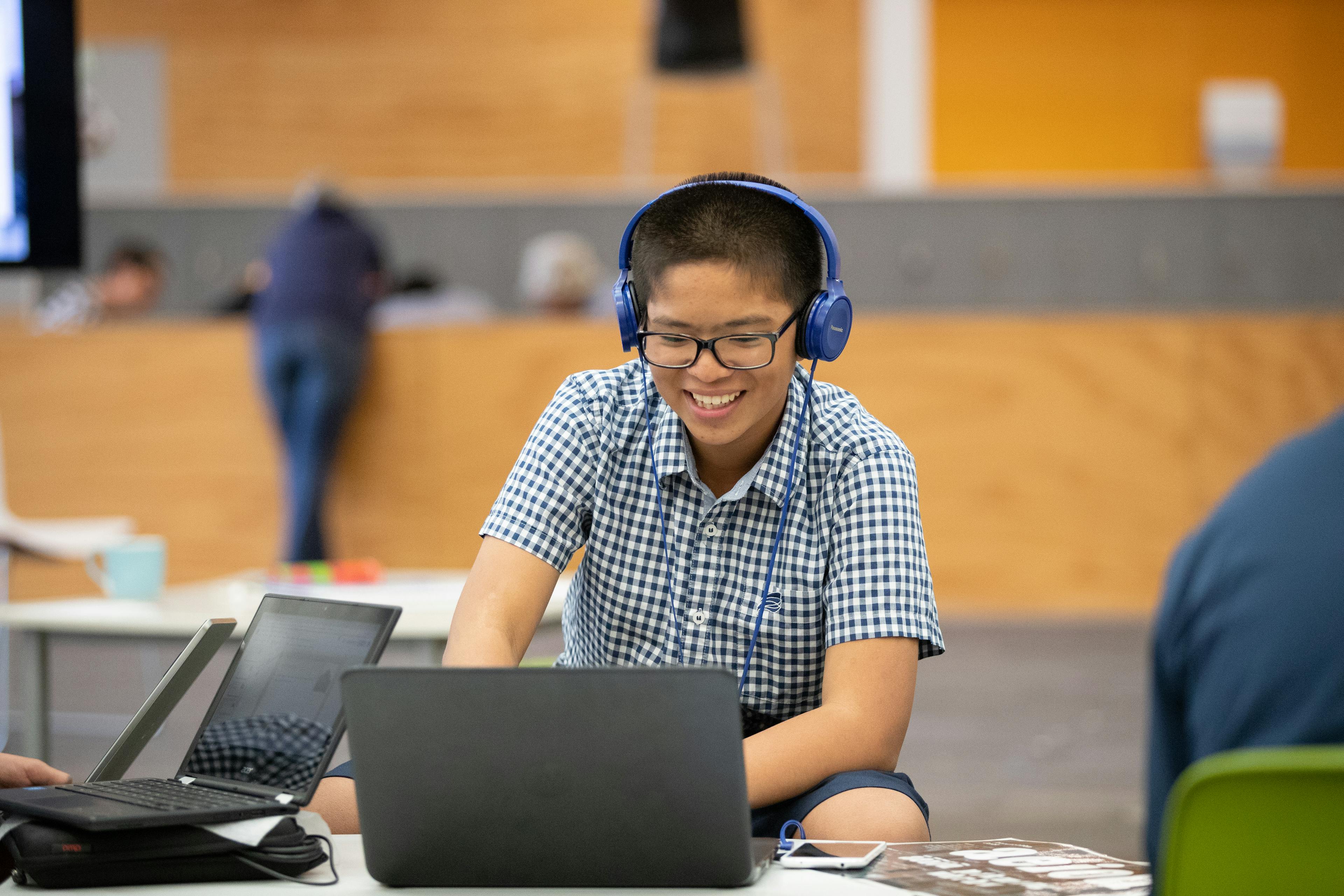 Image of student using a laptop and headphones