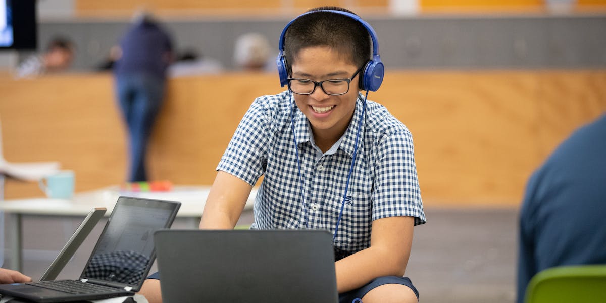 Image of student using a laptop and headphones