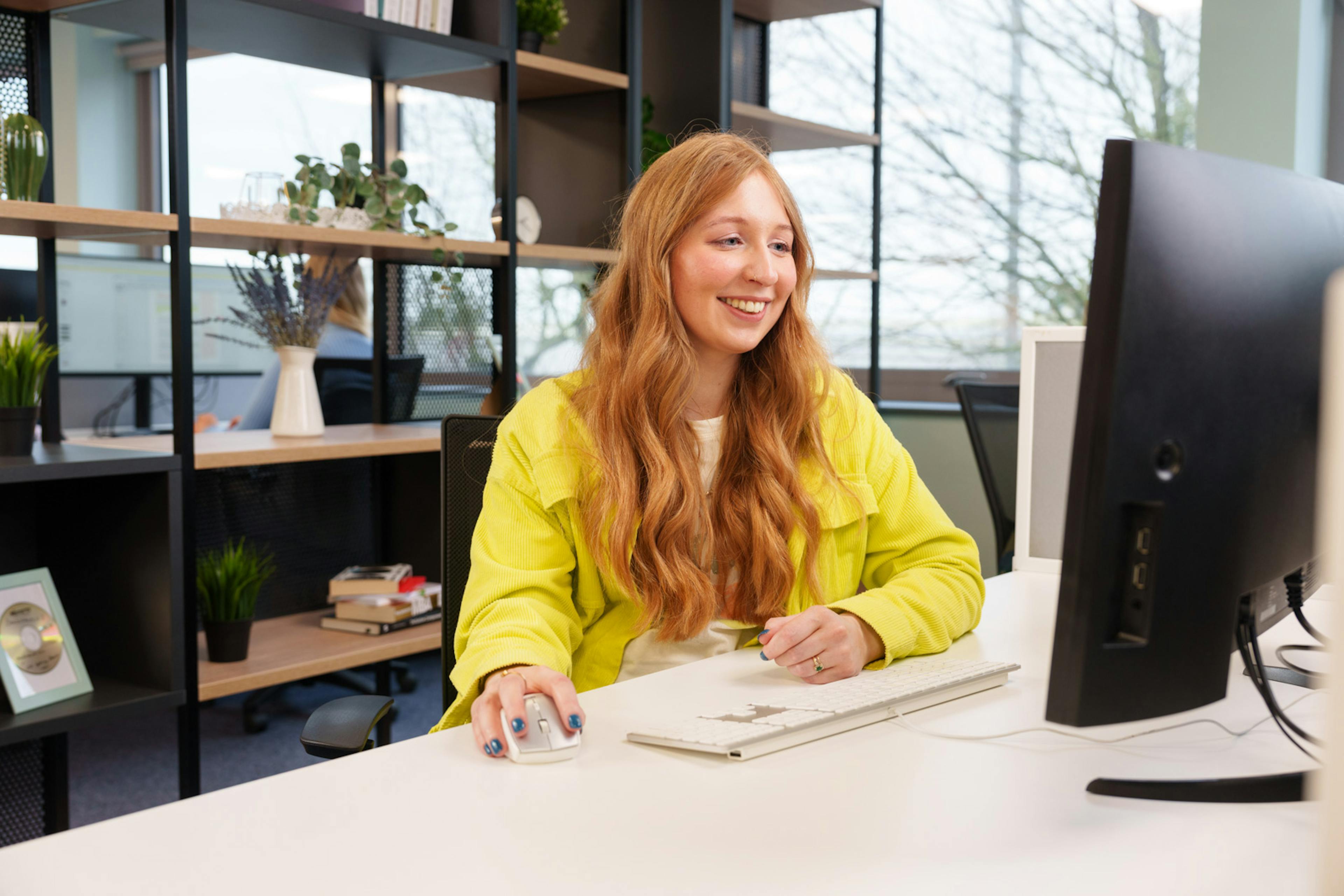 A smiling employee in an office working at a computer