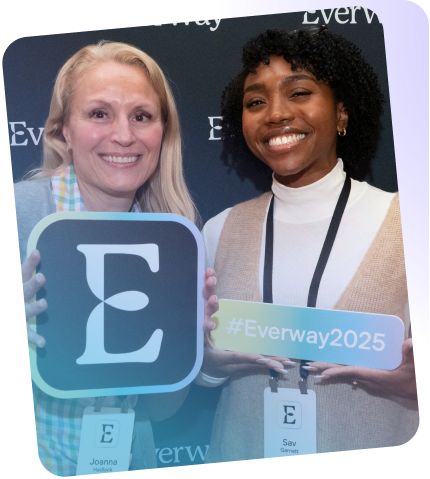 Two Everway employees pose for a photo with some branded signage
