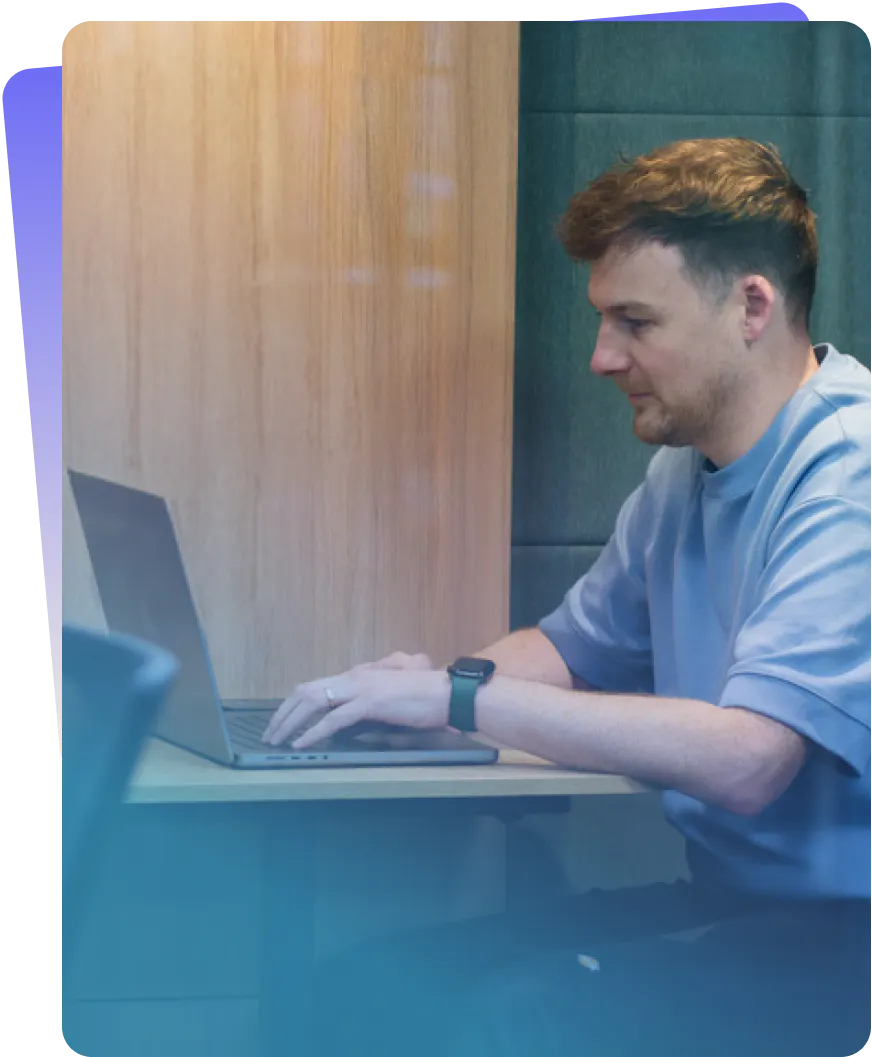 An Employee working on a laptop in a meeting booth