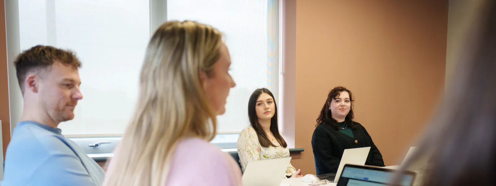 A team meeting setting, four individuals sitting around a meeting room