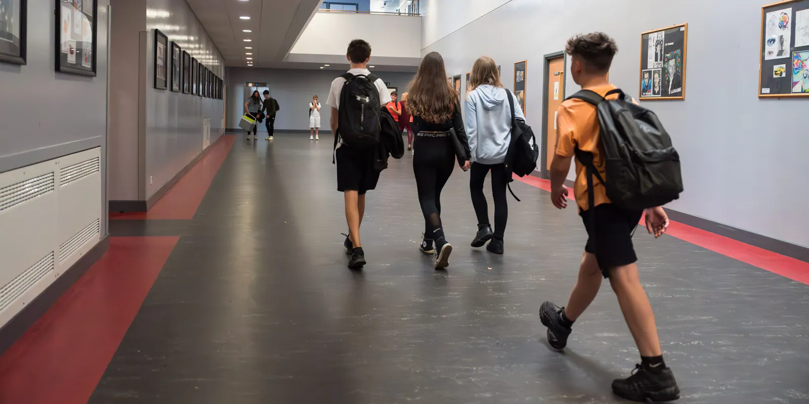 Four students walking through a school hallway