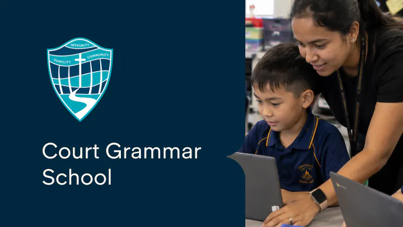 Teaching assistant supporting primary school aged student on laptop
