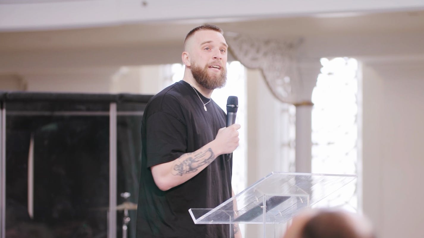 A screen capture of Joshua Luke Smith's spoken word performance, "On Lament." He is midway through a verse and look out towards the audience. 