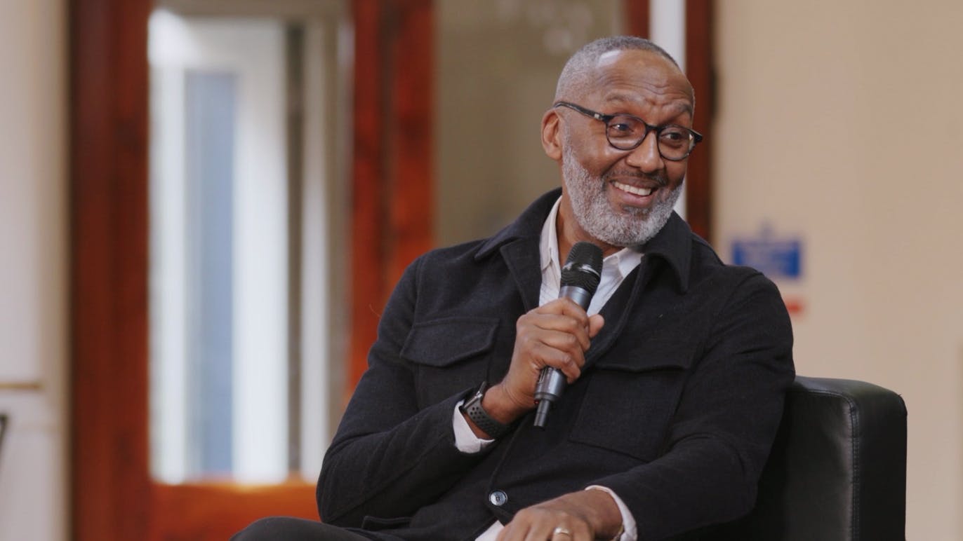 A screen capture of Leroy Logan's interview. He is smiling towards the interviewer while sharing an anecdote.