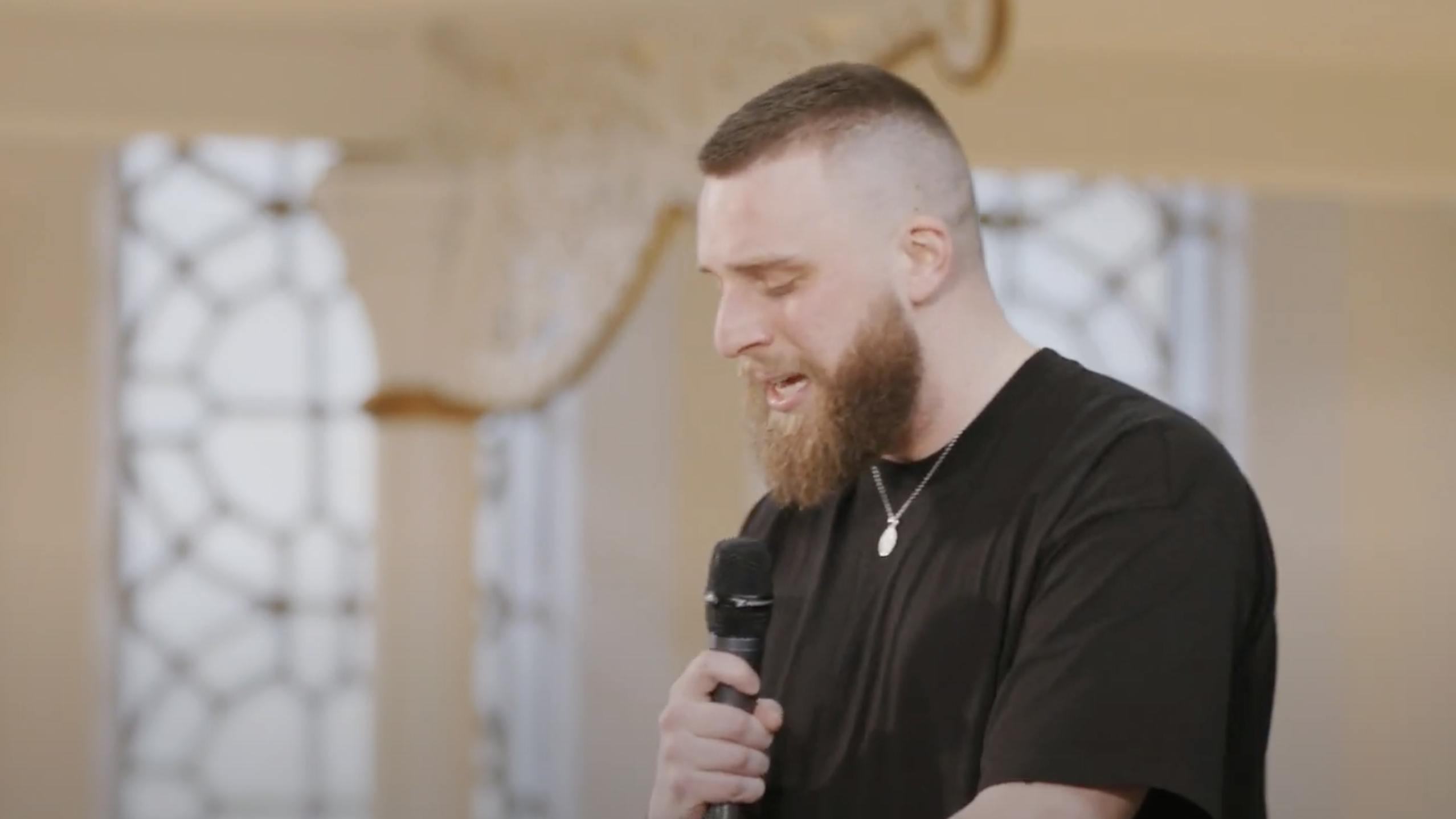 A screen capture of Joshua Luke Smith's performance. He has eyes closed in thought as he is speaking.