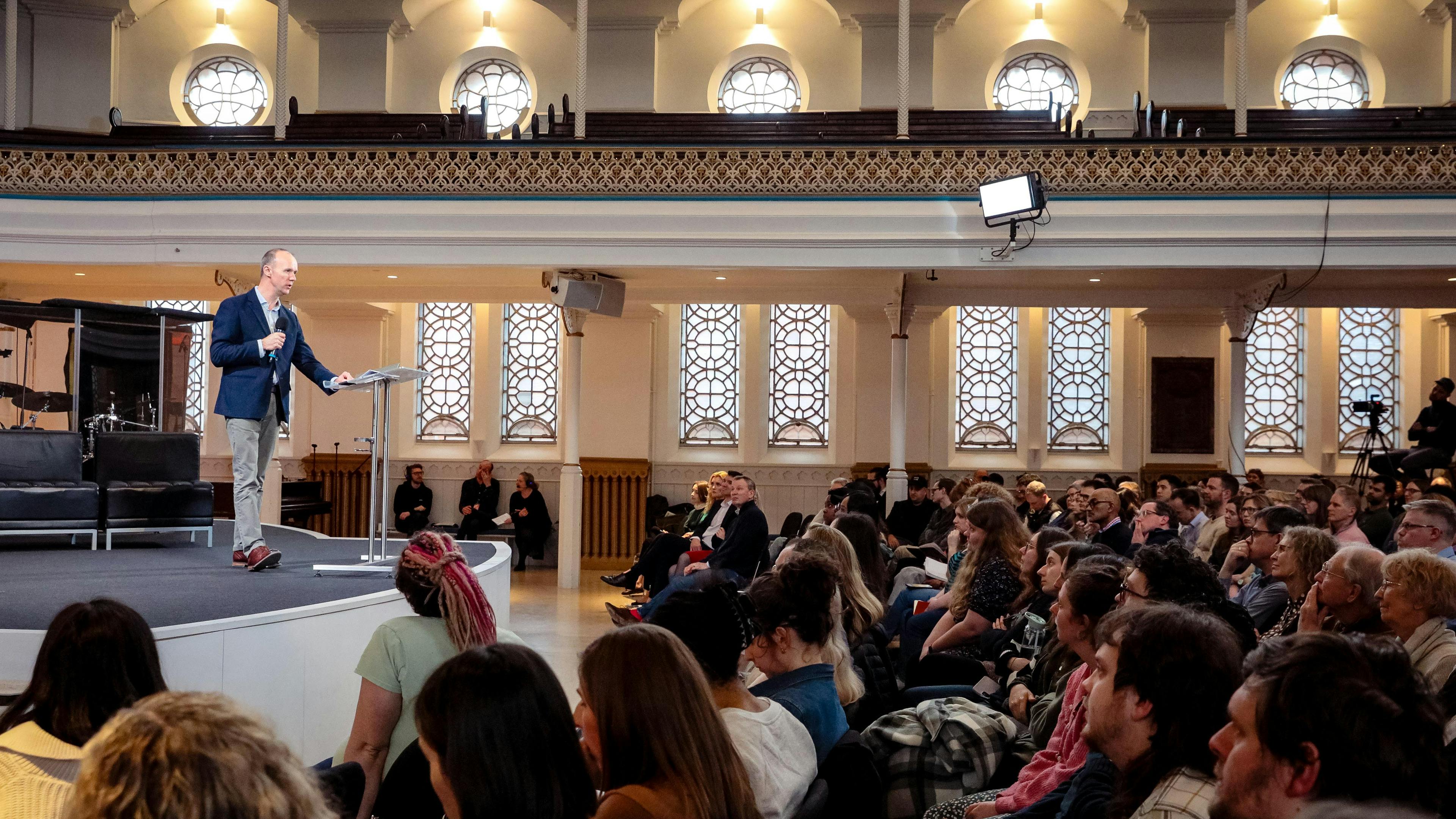 Paul Woolley standing on a stage talking to a crowd.