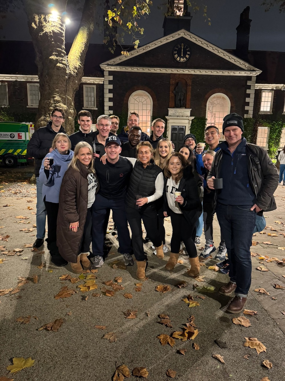 A group of participants standing outdoors at night, posing for a photo outside a historic building during the sleep out event.