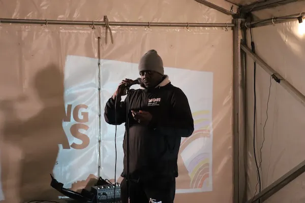 A speaker holding a microphone and addressing the audience inside the marquee.