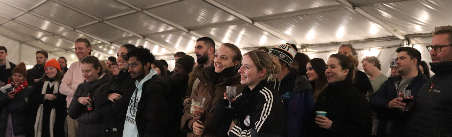 A group of participants standing inside a marquee, listening to a speaker during the sleep out event.