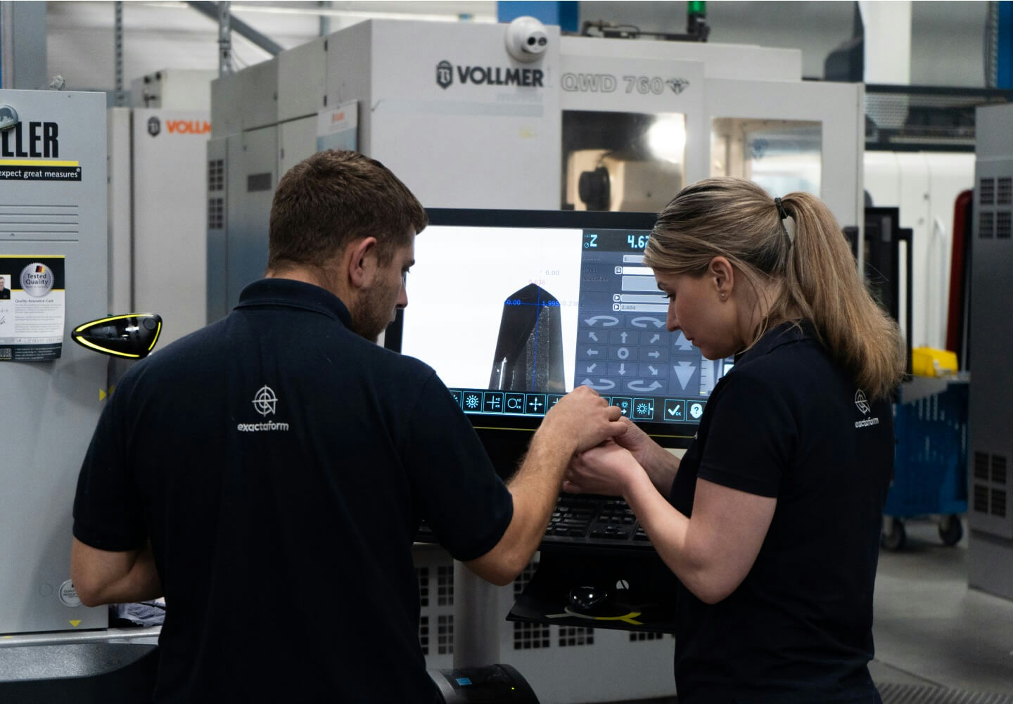 Exactaform Engineers looking at a computer screen in front of a tooling machine