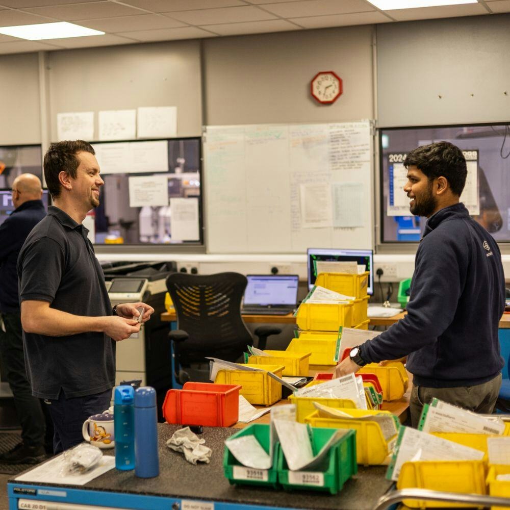 Exactaform employees talking to each other by a workstation