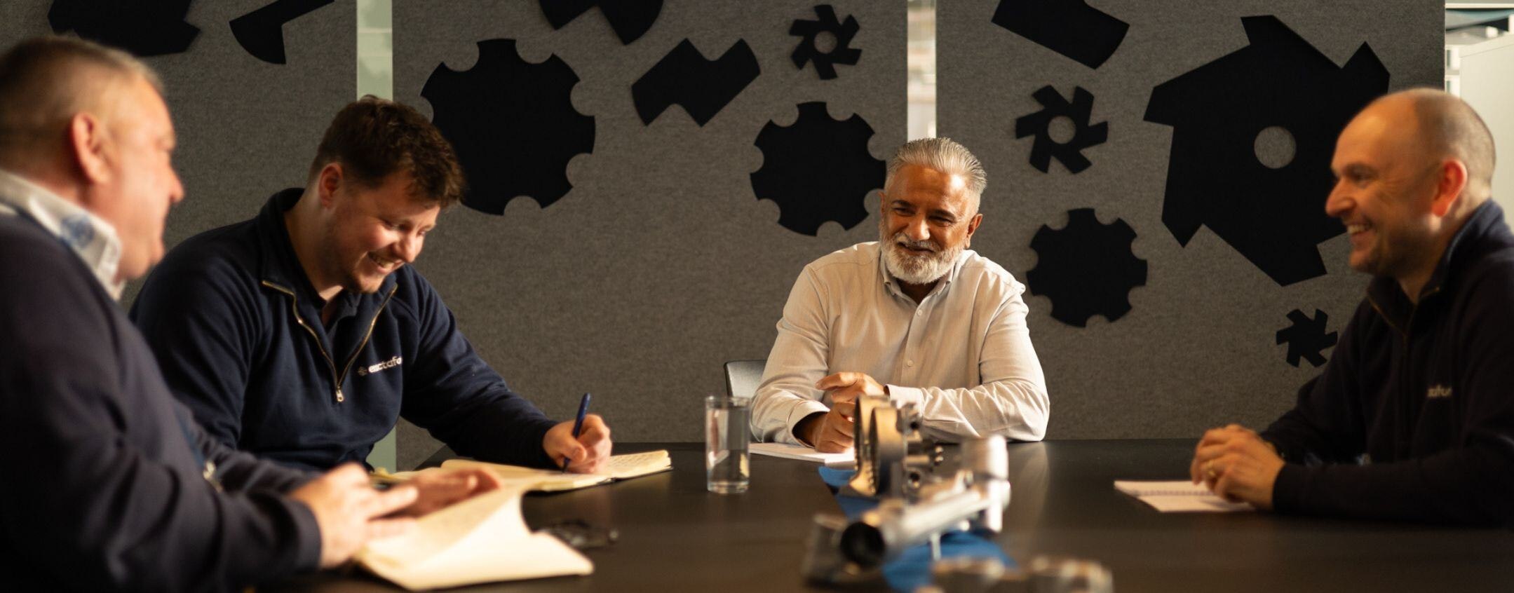 Exactaform employees sitting around a table talking