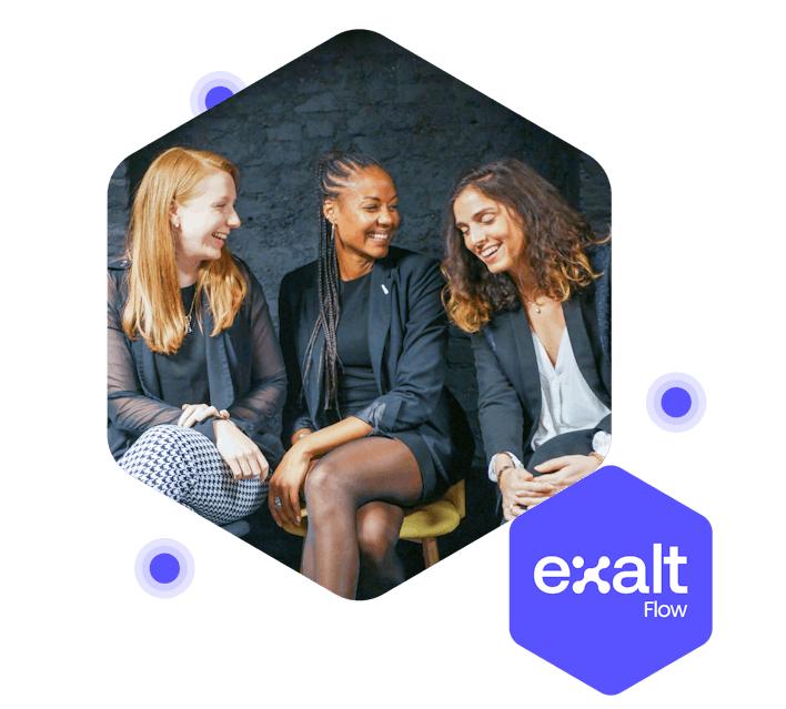 Tres personas sentadas y riendo juntas, con el logo de eXalt Flow a su lado.