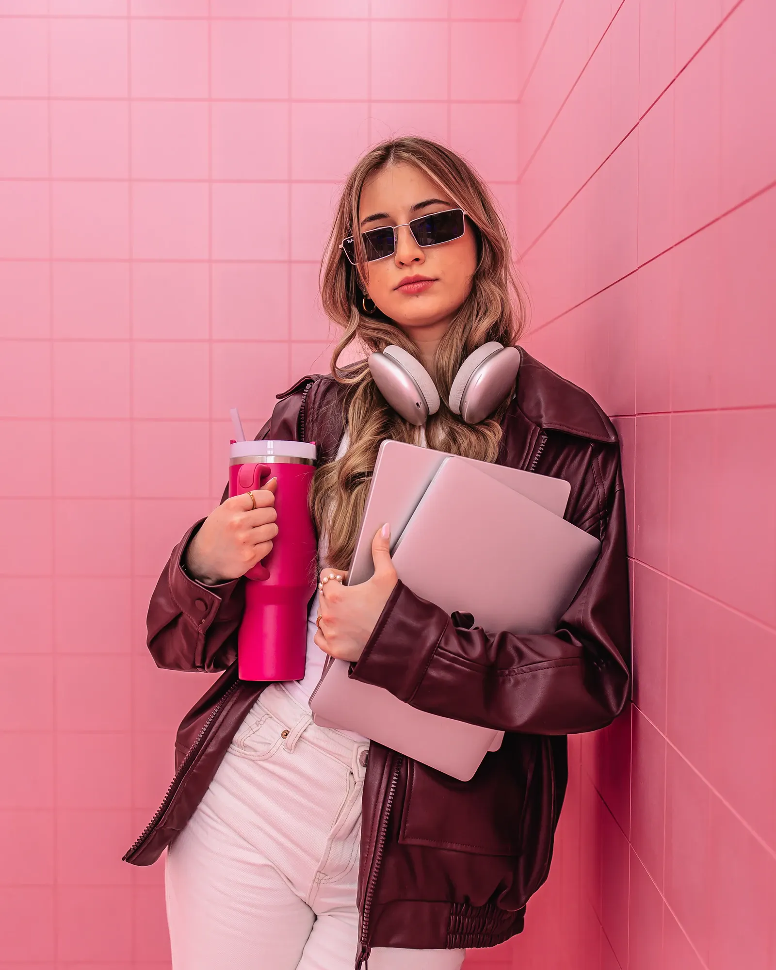 Exportarts Mitarbeiterin lehnt mit Macbook an eine pinke Wand