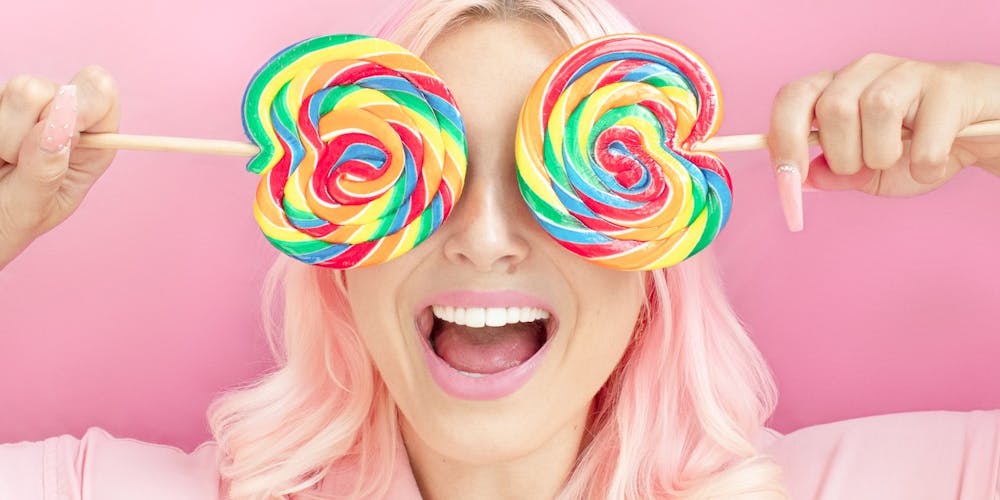 Frau hält sich bunte Lollipops vor die Augen Frau hält sich bunte Lollipops vor die Augen