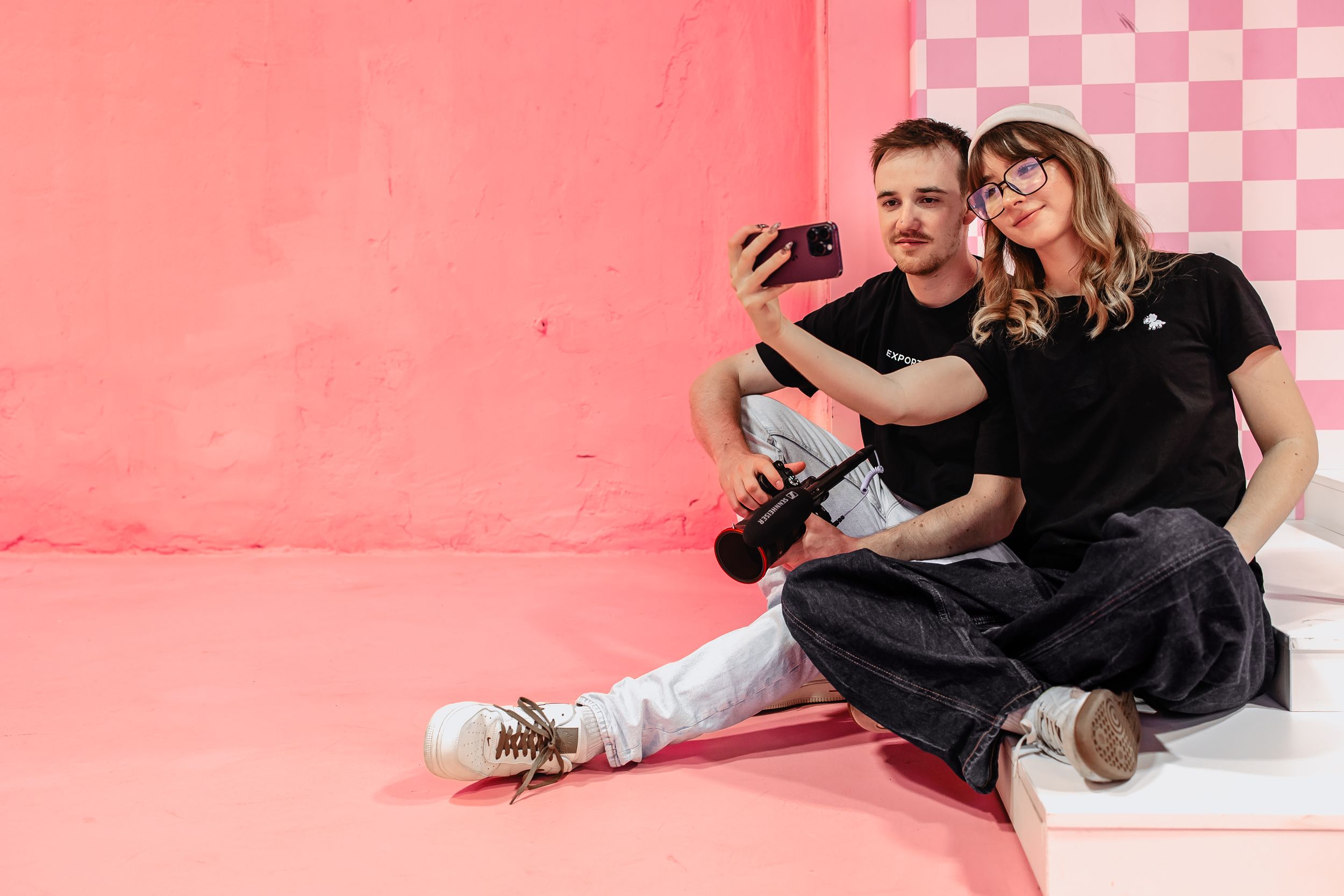 Zwei Mitarbeiter der Social Ads Agentur Exportarts machen ein Selfie vor einer pinken Wand